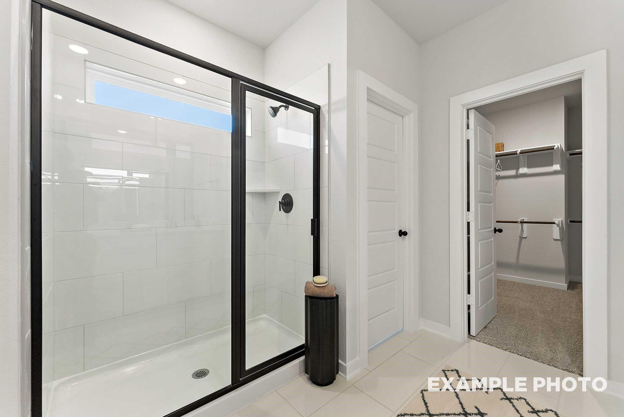 Modern walk-in shower with black trim and spacious walk-in closet in The Everett E floor plan, Sundance Cove, Crosby, TX.