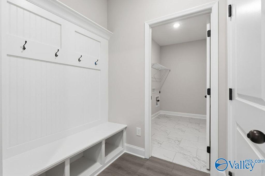 Spacious mudroom with white shiplap walls, coat hooks, built-in bench, and laundry nook in Davidson Homes The Rockford B, Hartselle, Alabama