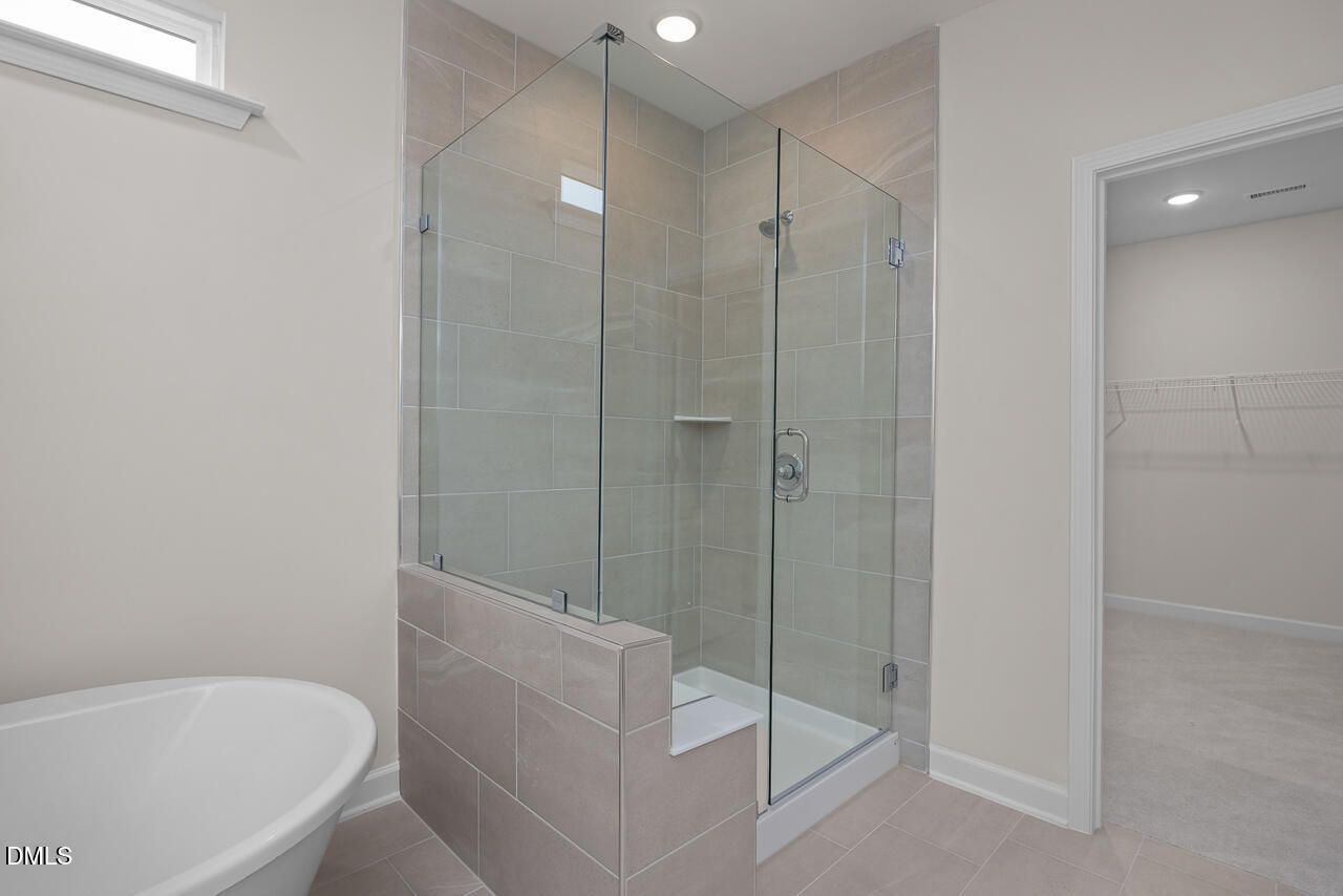 Modern master bathroom featuring frameless glass shower and freestanding tub in Davidson Homes The Cypress D II, Angier, NC