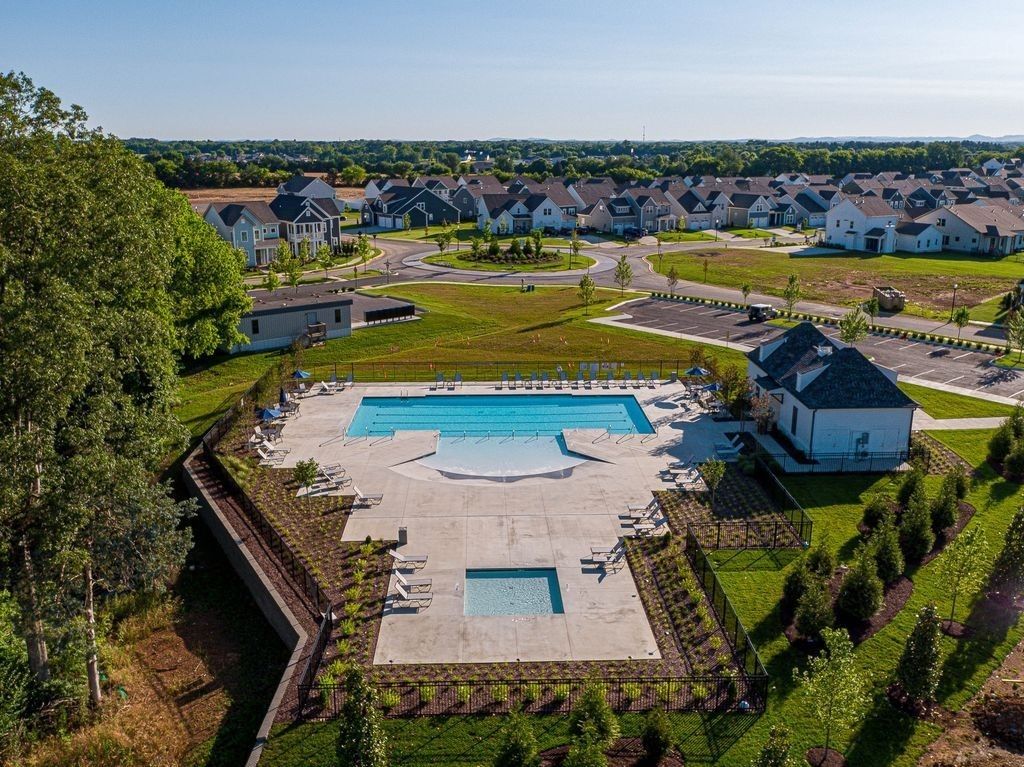 Aerial view of sparkling community pool with lounge chairs, umbrellas, and pathways surrounded by modern homes in Shelton Square, Murfreesboro, Tennessee