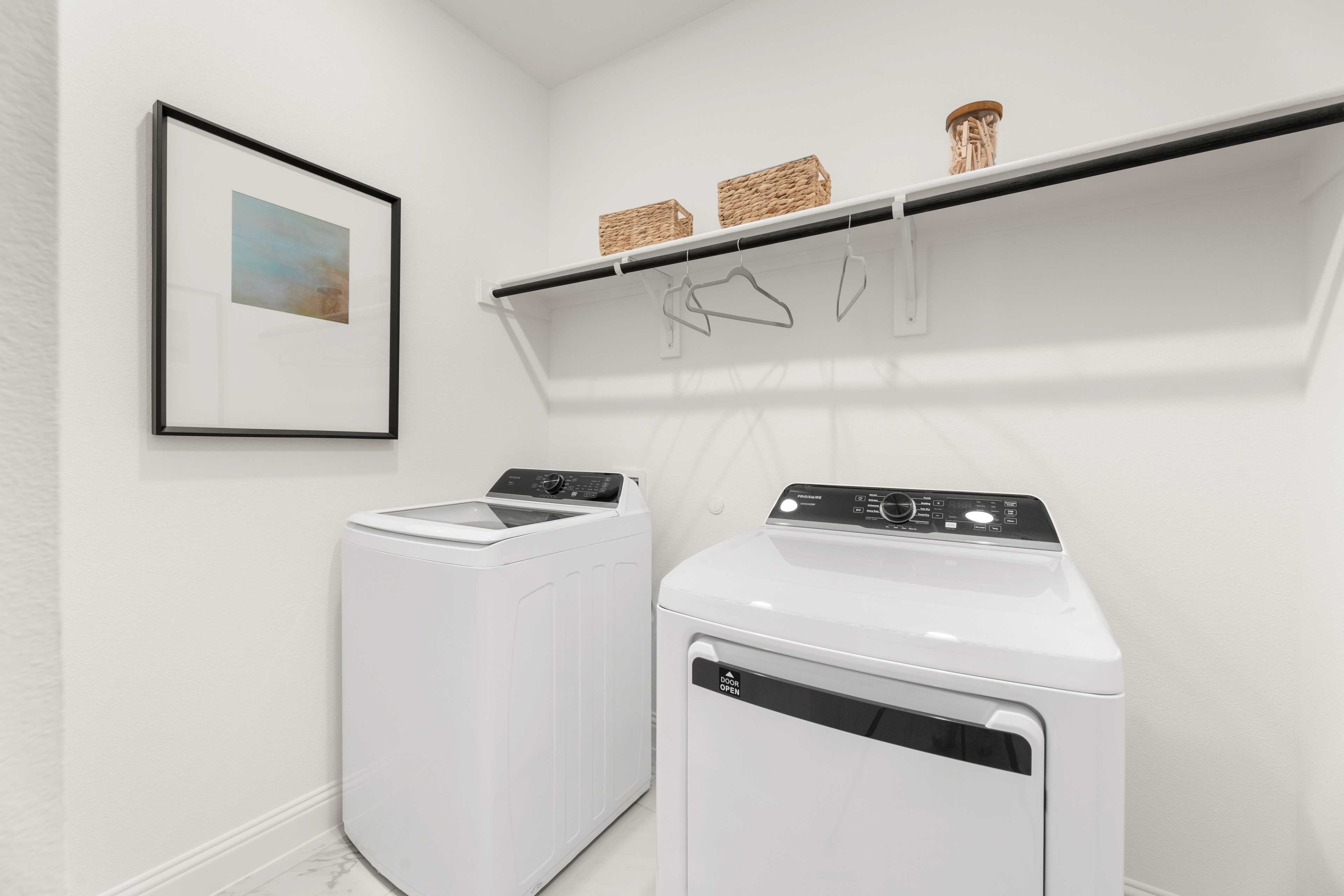 Spacious laundry room with white washer dryer set, built-in shelves, wicker baskets at Meadow Ridge Estates in Josephine Texas