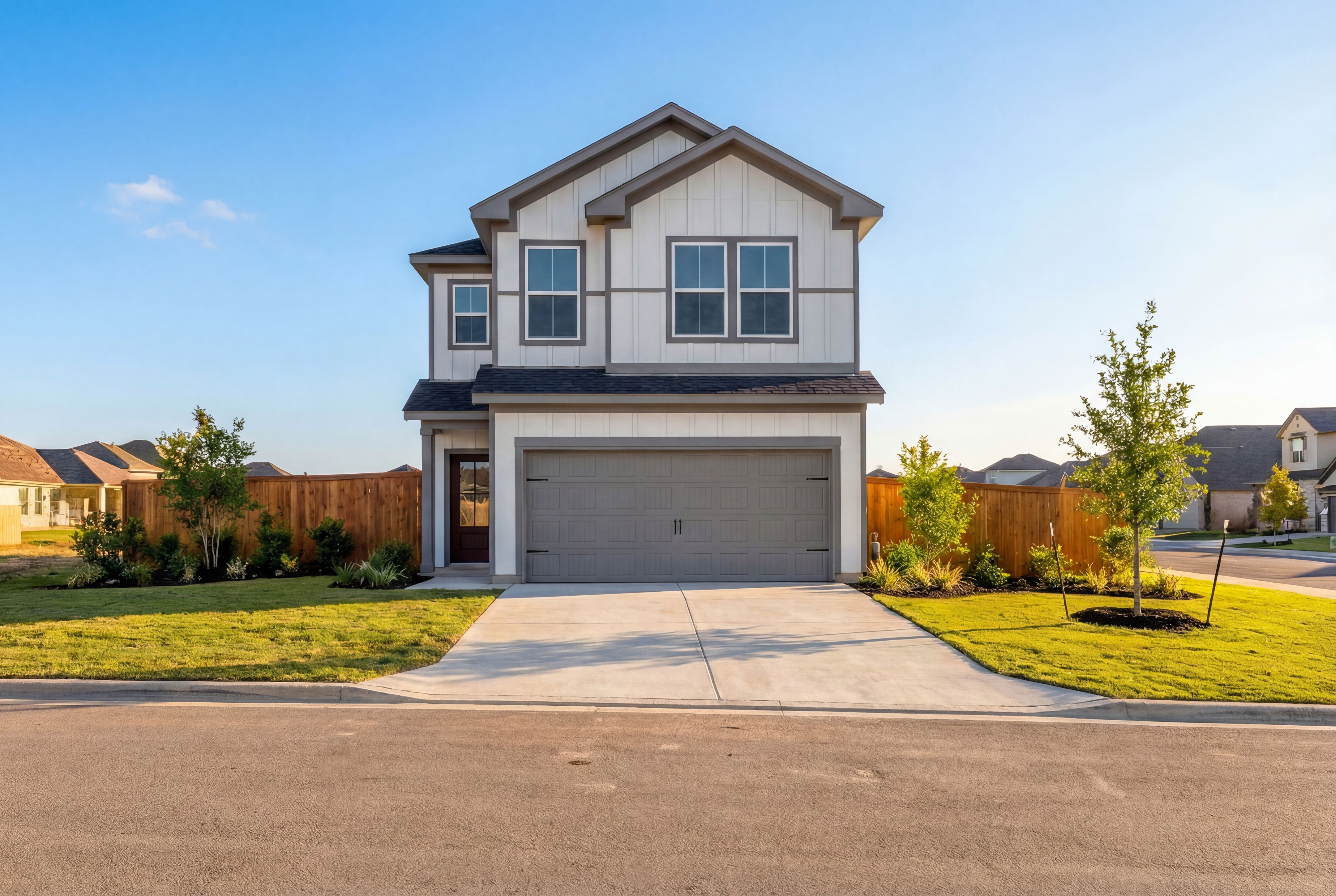 Two-story The Gillian C elevation featuring white shiplap siding, dark trim, two-car garage, and landscaped yard in San Antonio