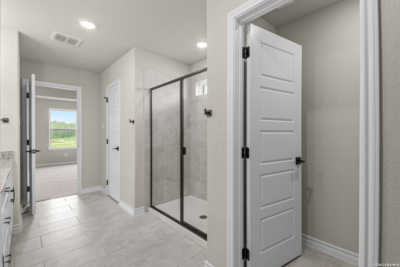 Modern bathroom with glass-enclosed walk-in shower in The Danbury H floor plan at The Reserve at Potranco Oaks, Castroville.