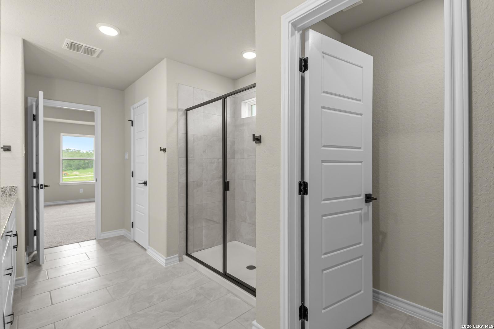 Modern bathroom with glass-enclosed walk-in shower in The Danbury H floor plan at The Reserve at Potranco Oaks, Castroville.