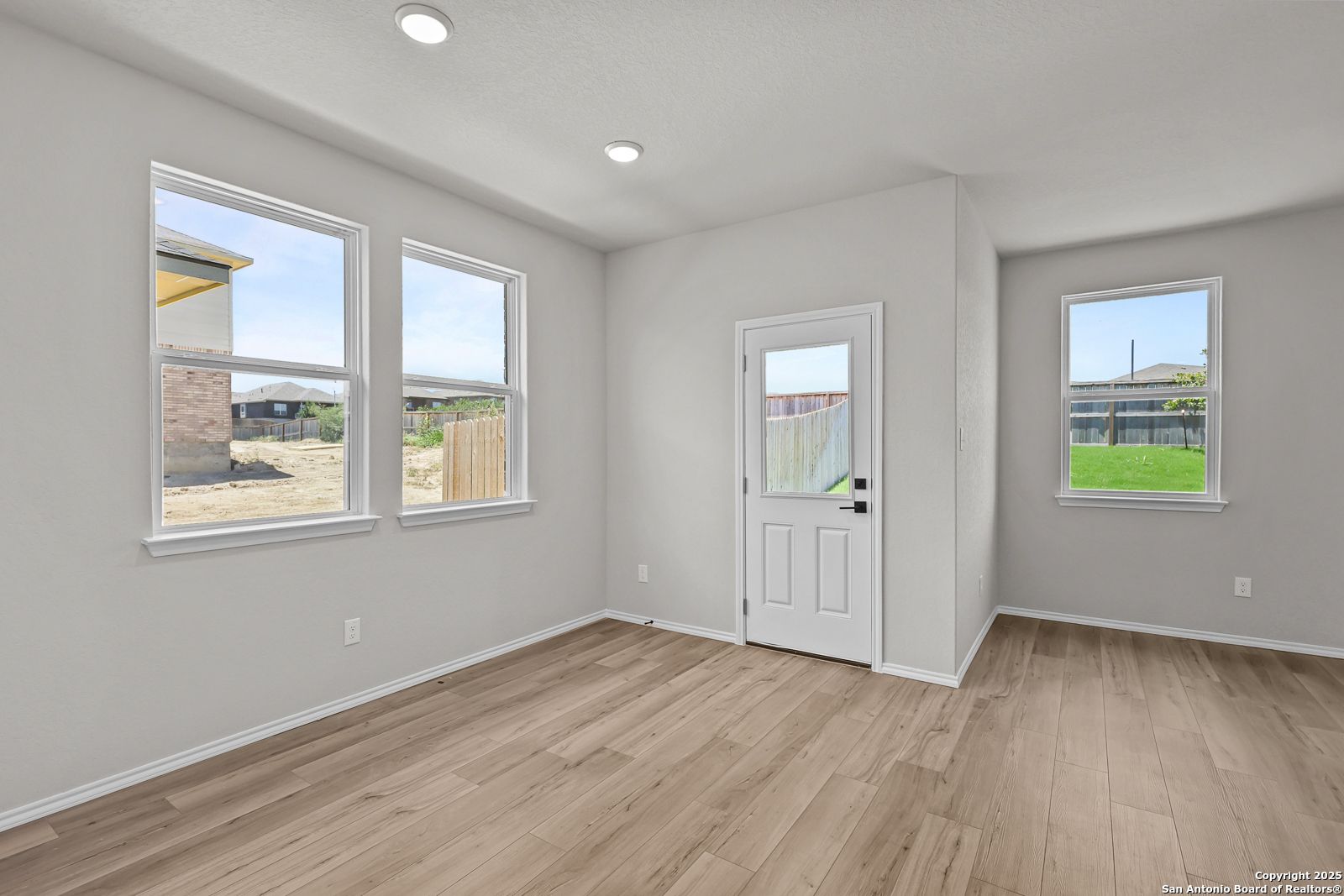 Spacious empty bedroom with large windows, hardwood floors, and neutral walls in Davidson Homes The Daphne K, San Antonio, Texas