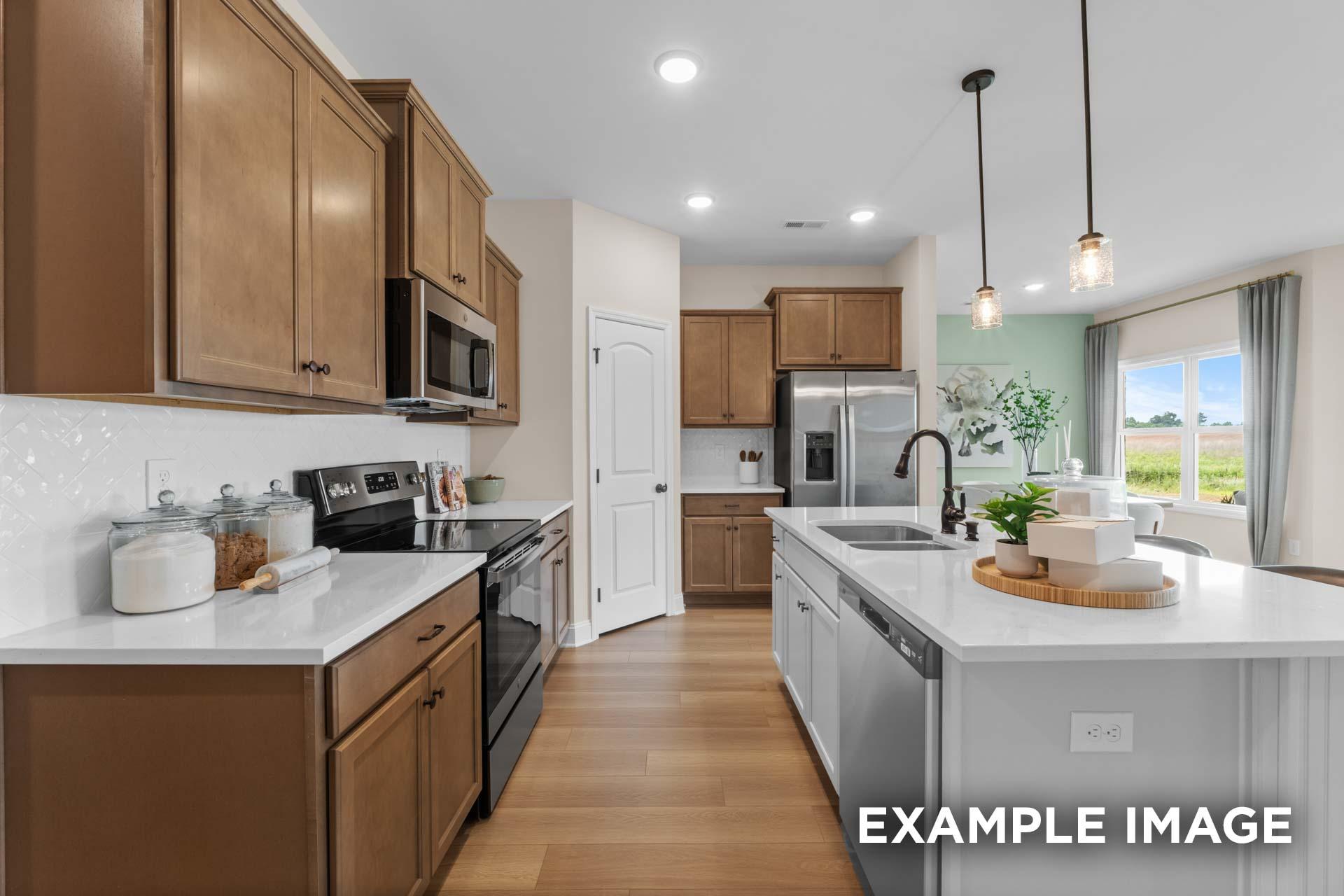 The Laurel M kitchen featuring warm shaker cabinets, white quartz island with sink, stainless steel appliances, and pendant lights