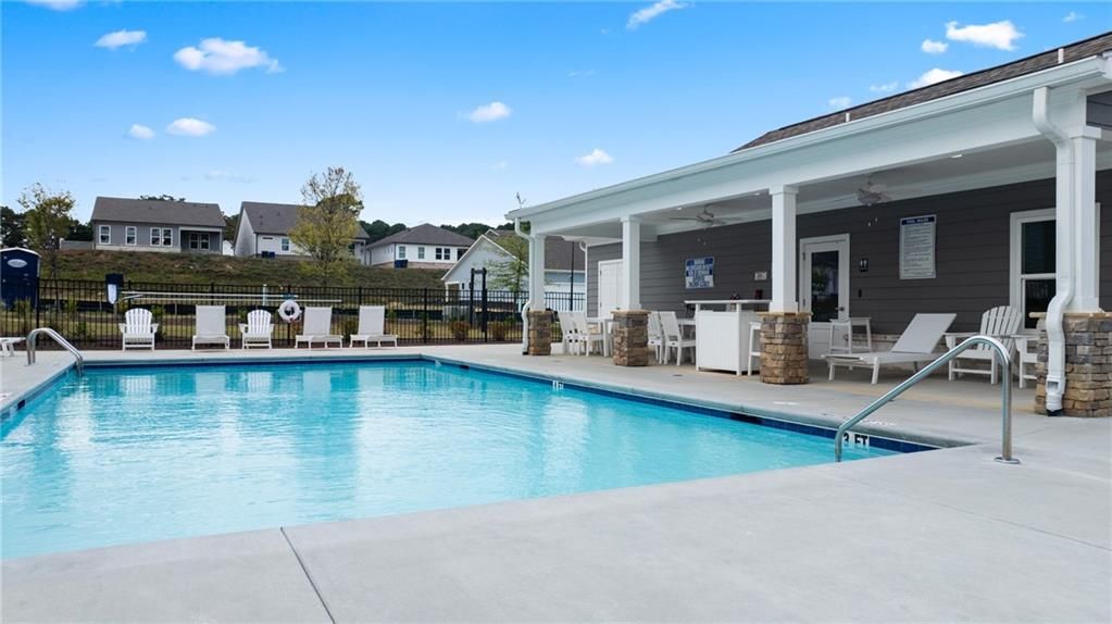Crystal-clear community pool with lounge chairs and covered patio amid homes in Kelly Preserve, Loganville, Georgia