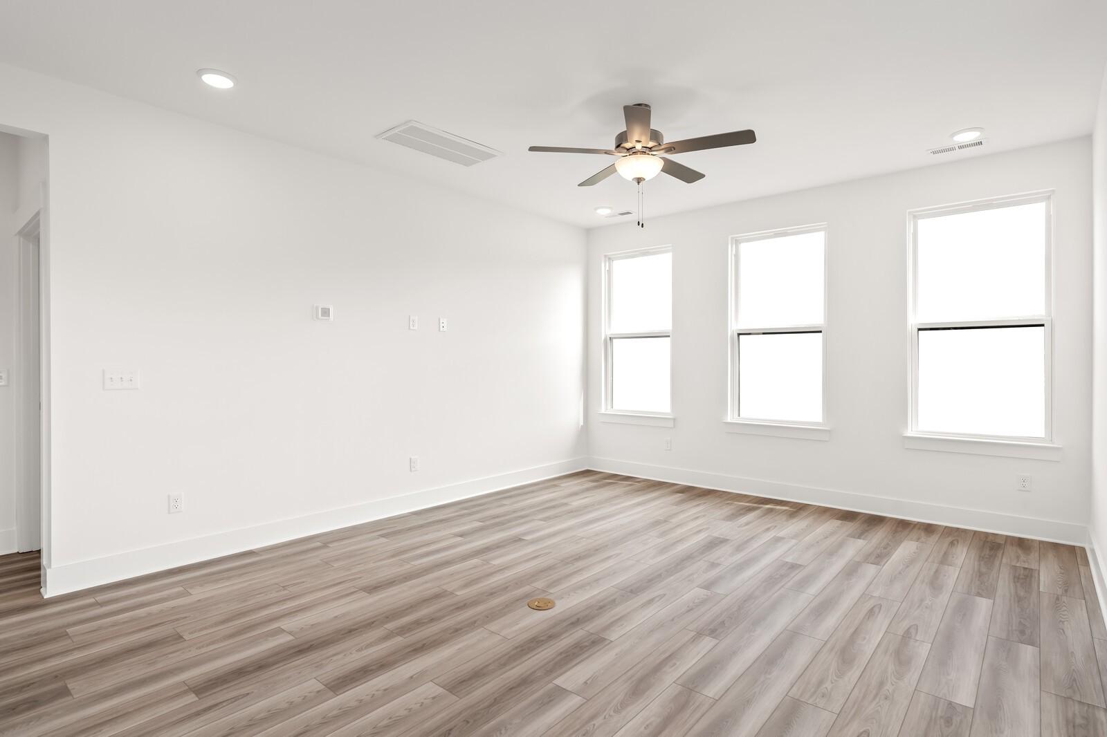 Bright upstairs room with white walls, three large windows, ceiling fan, and light hardwood floors in Davidson Homes The Ash C, Mt. Juliet