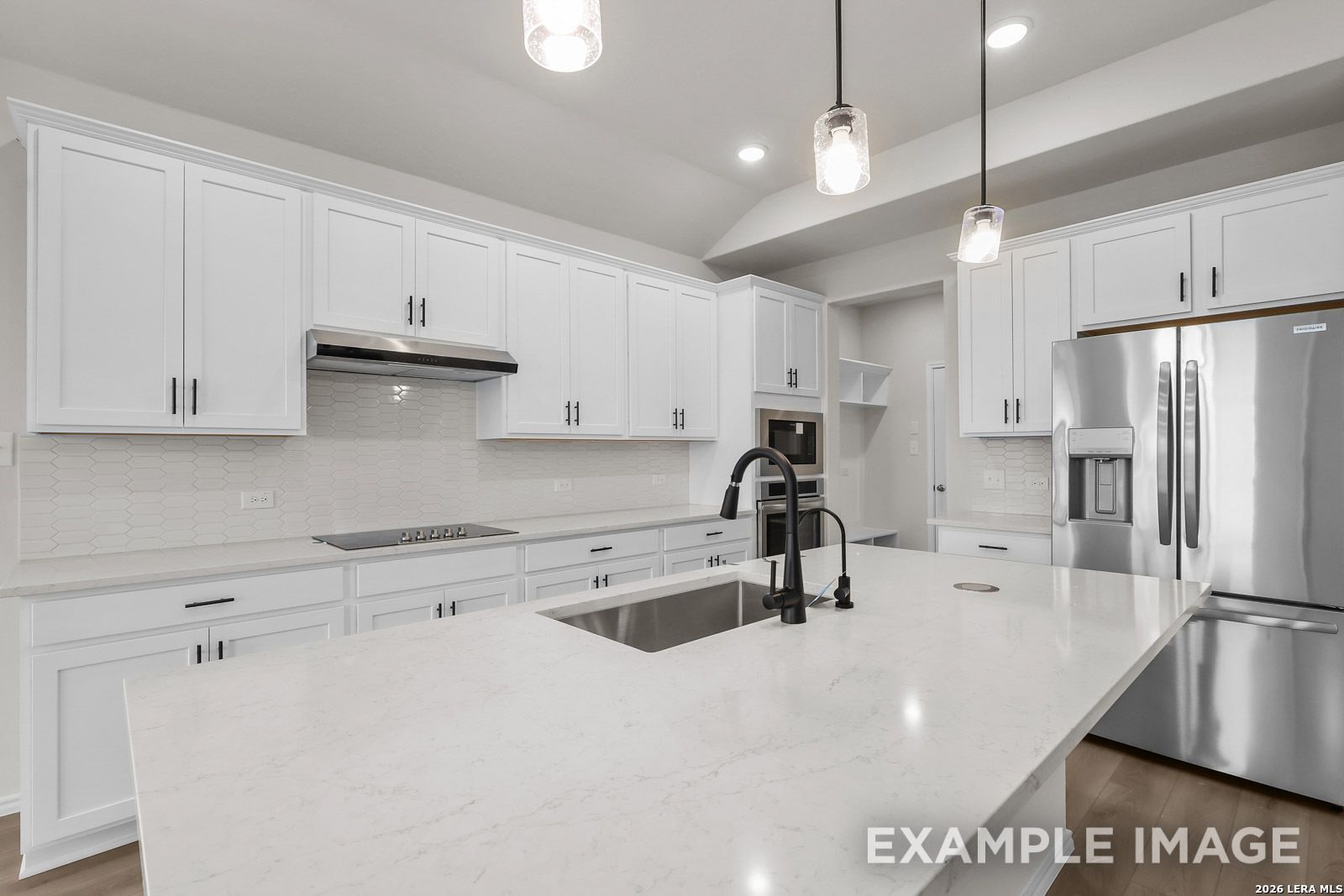 Modern white kitchen with quartz island, stainless appliances, and pendant lighting in Davidson Homes' The Sequoia C floor plan.
