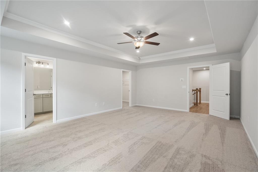 Spacious upstairs bedroom with ceiling fan, en-suite bath, and carpeted floors in Davidson Homes The Cary A, Kennesaw, Georgia
