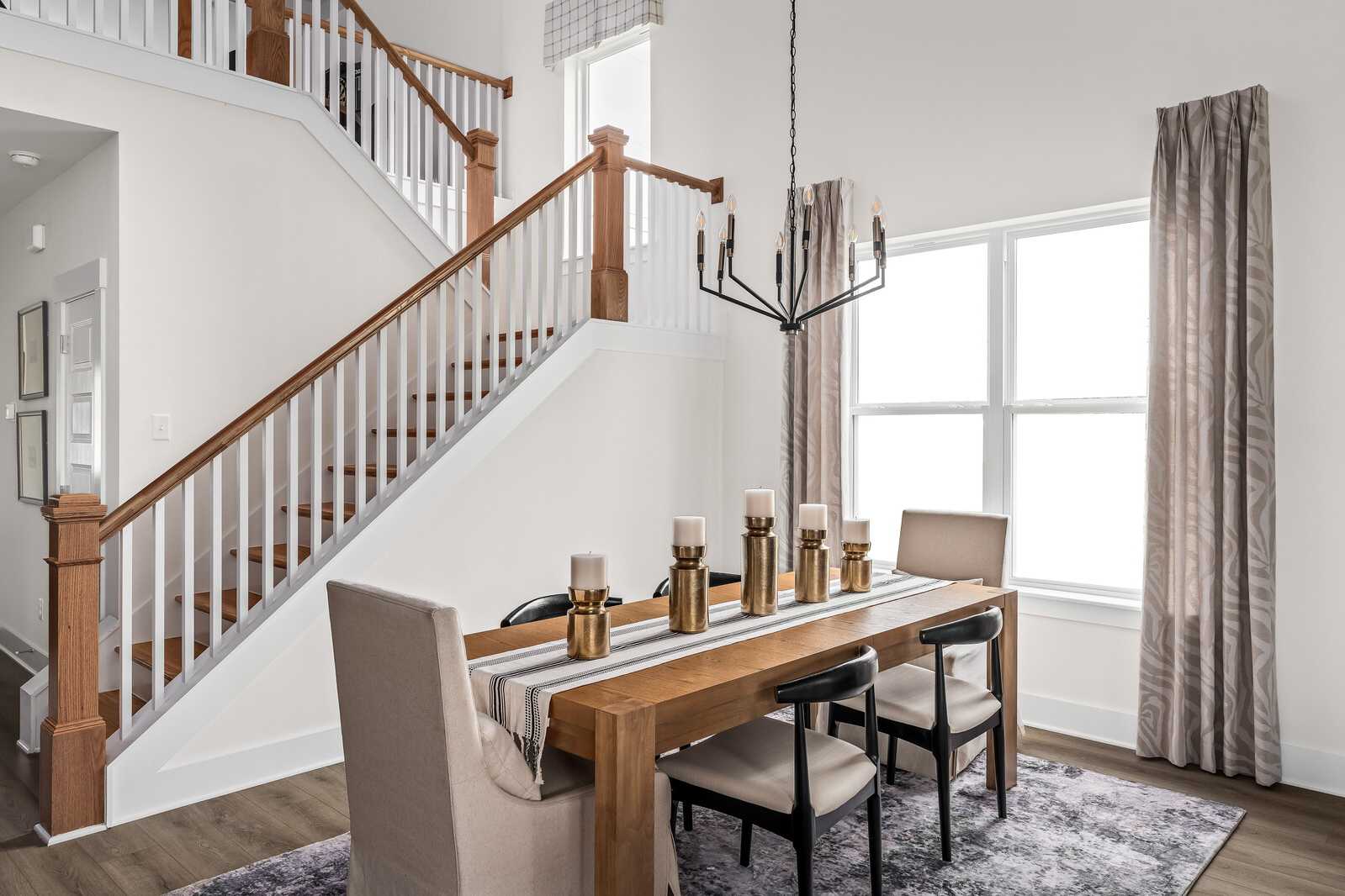 Elegant dining room at Woods Crossing in Gallatin TN with wooden table, chandelier, candles and open staircase by Davidson Homes