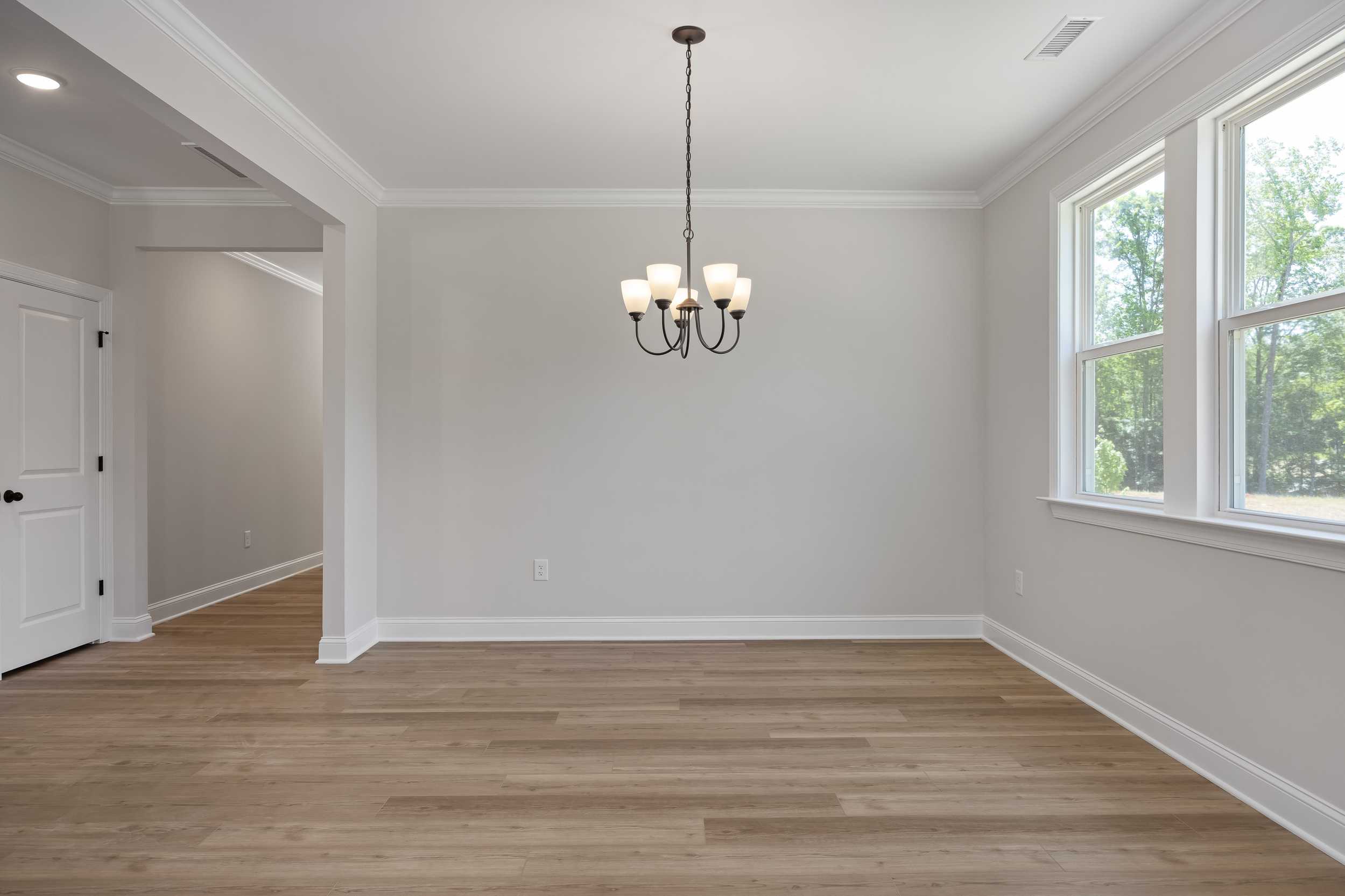 Spacious dining room in The Beech C with hardwood floors, modern chandelier, large windows, and open layout