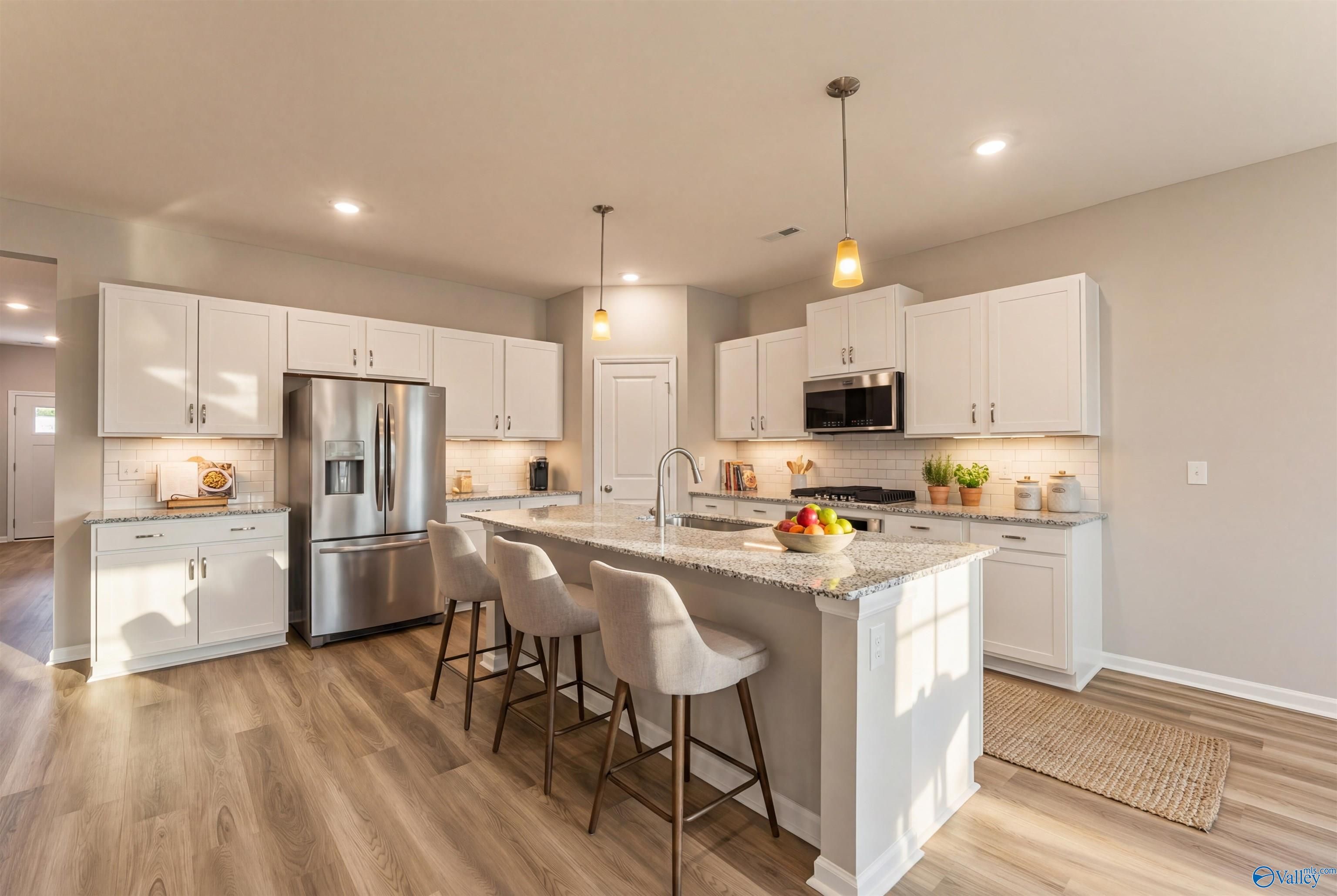 Modern white kitchen island with stainless appliances, pendant lights in Davidson Homes The Phoenix, Hazel Green, AL