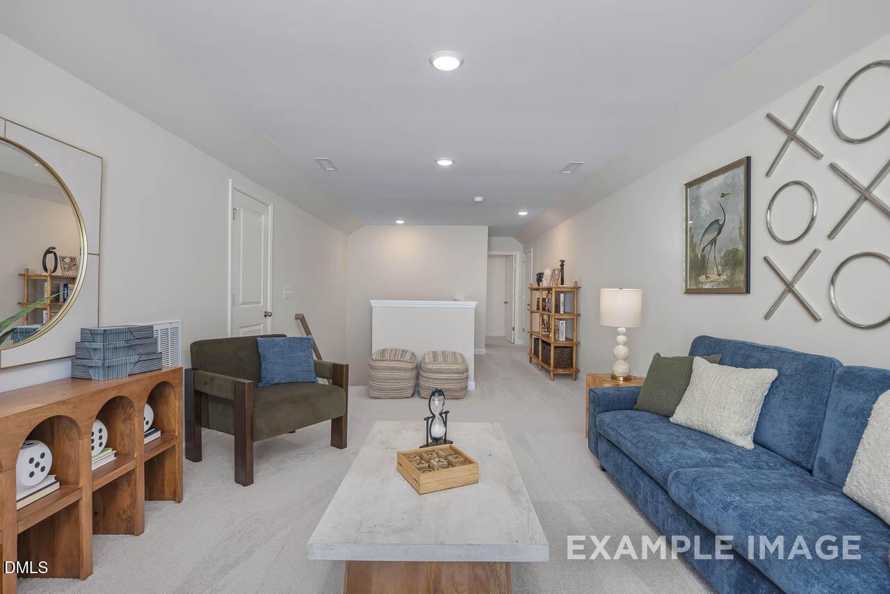 Cozy bonus room with blue velvet sectional sofa, gold XOXO mirror, and plush seating in Davidson Homes The Hickory II C, Wake Forest, NC