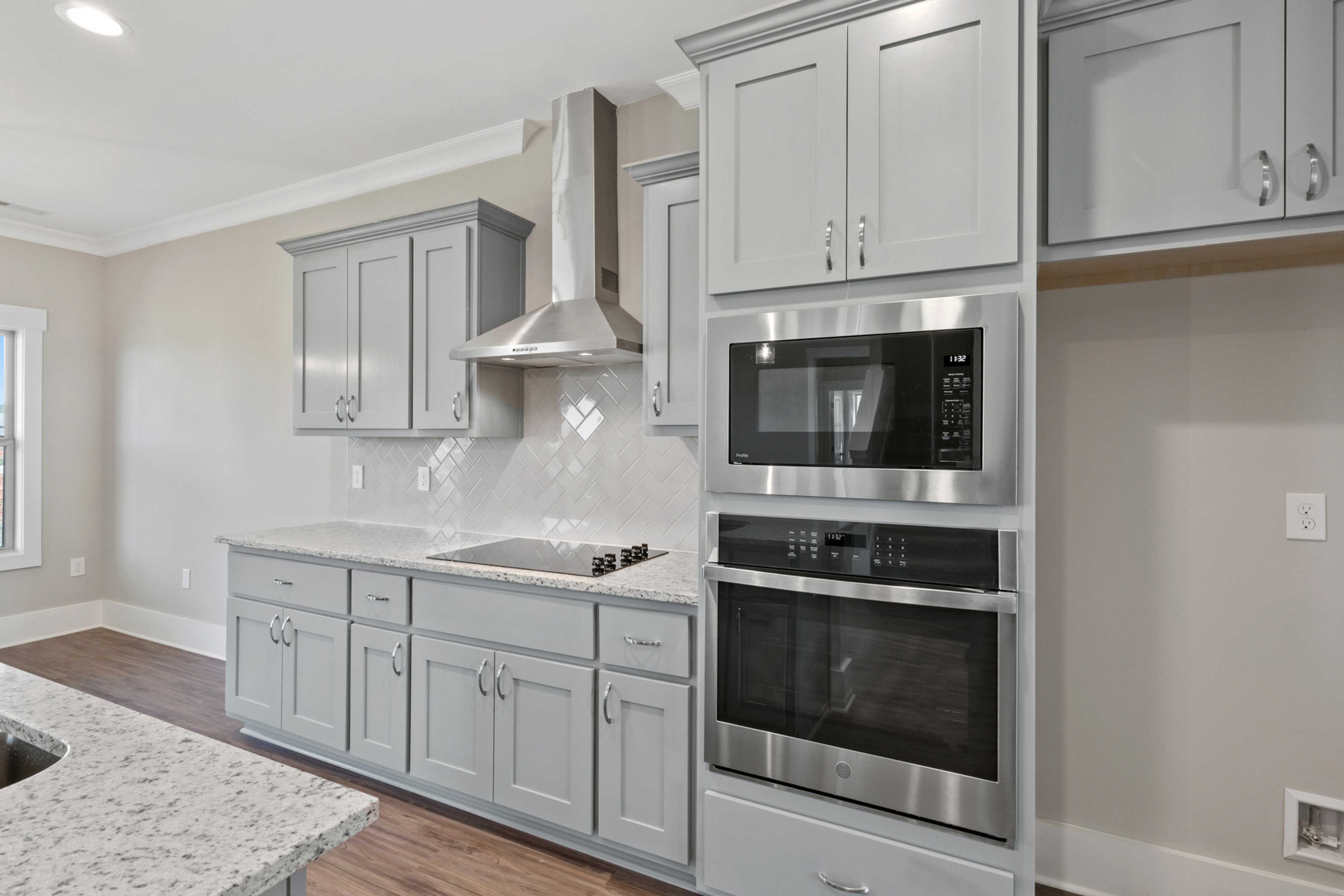 Modern kitchen in Little Burwell Estates, Harvest AL with gray shaker cabinets, stainless steel appliances, quartz island and subway tile backsplash