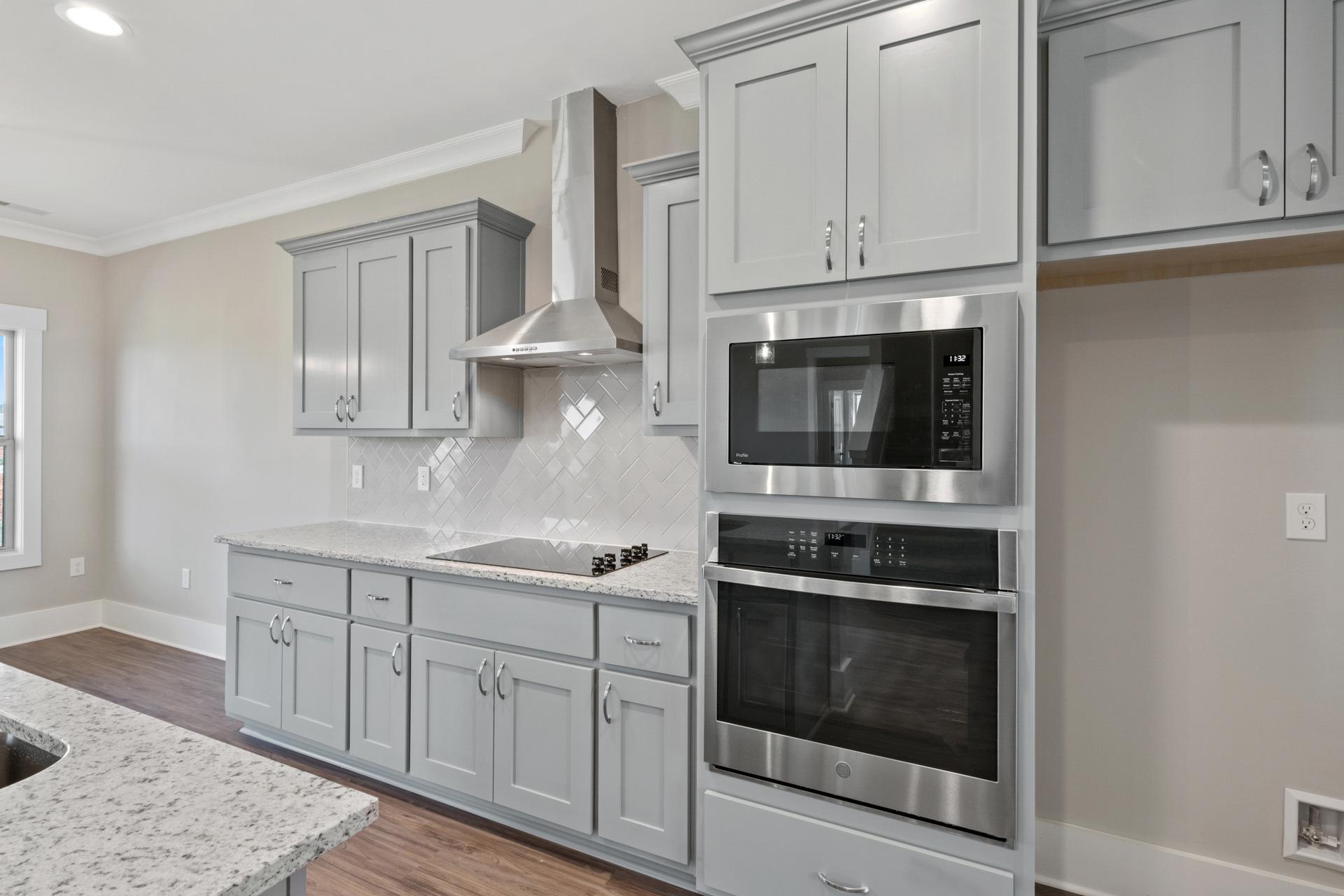 Modern kitchen in Little Burwell Estates, Harvest AL with gray shaker cabinets, stainless steel appliances, quartz island and subway tile backsplash