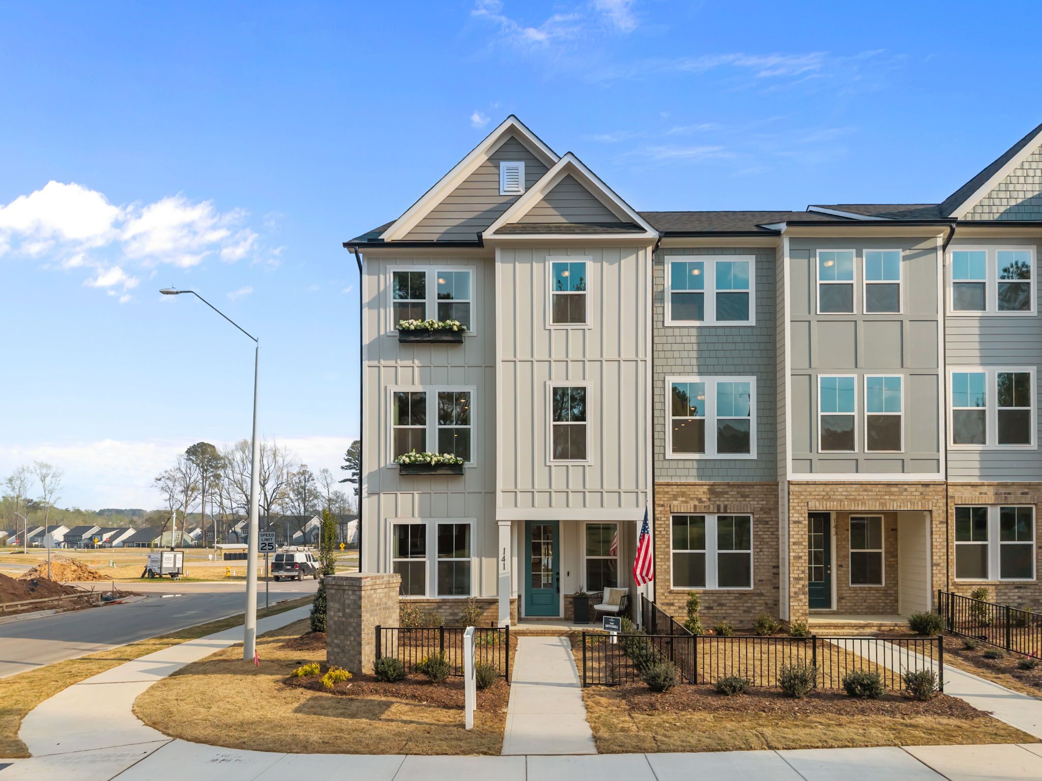 Modern townhomes at Camden Park in Knightdale NC with gray siding brick accents flower boxes and American flag