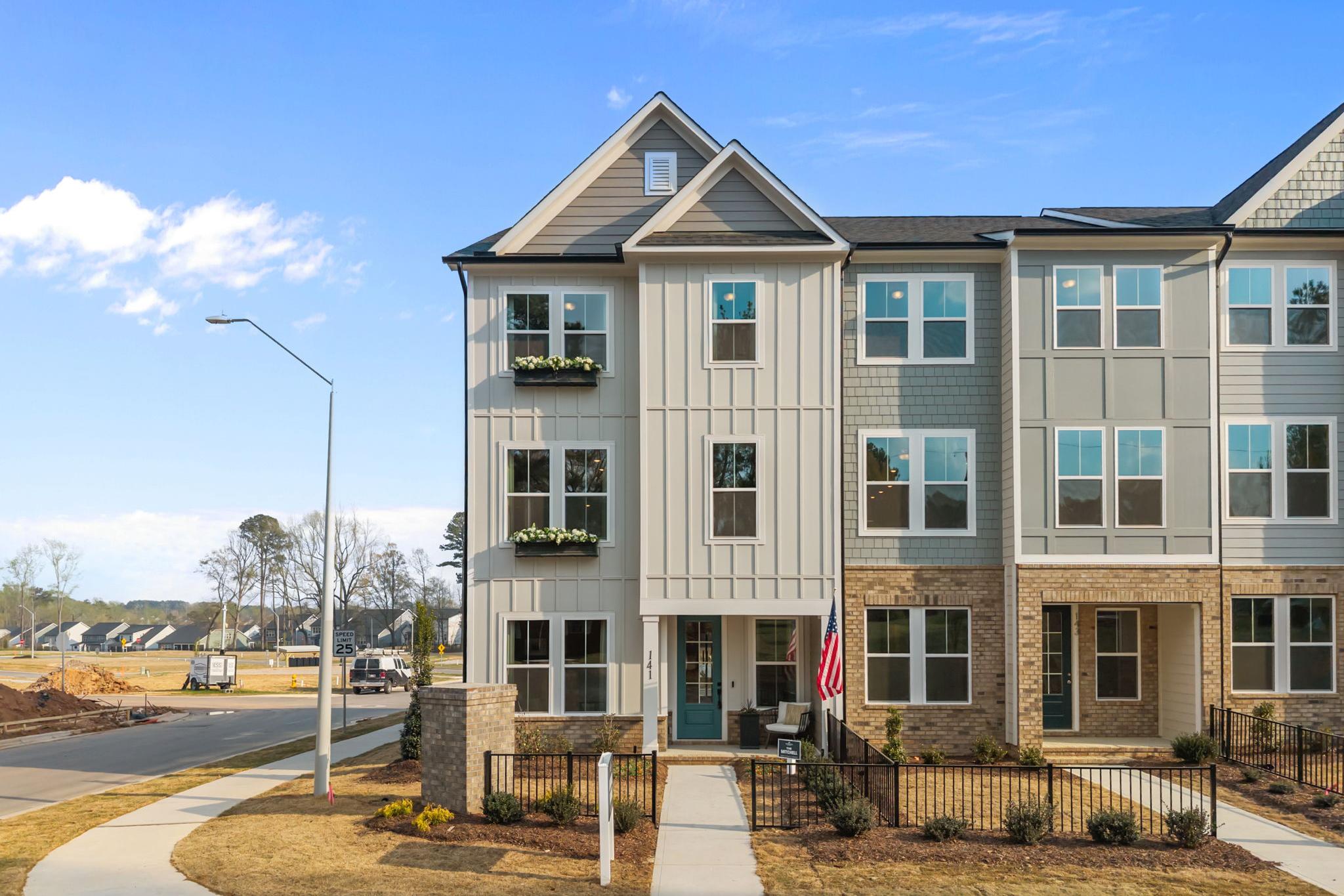 Modern townhomes at Camden Park in Knightdale NC with gray siding brick accents flower boxes and American flag
