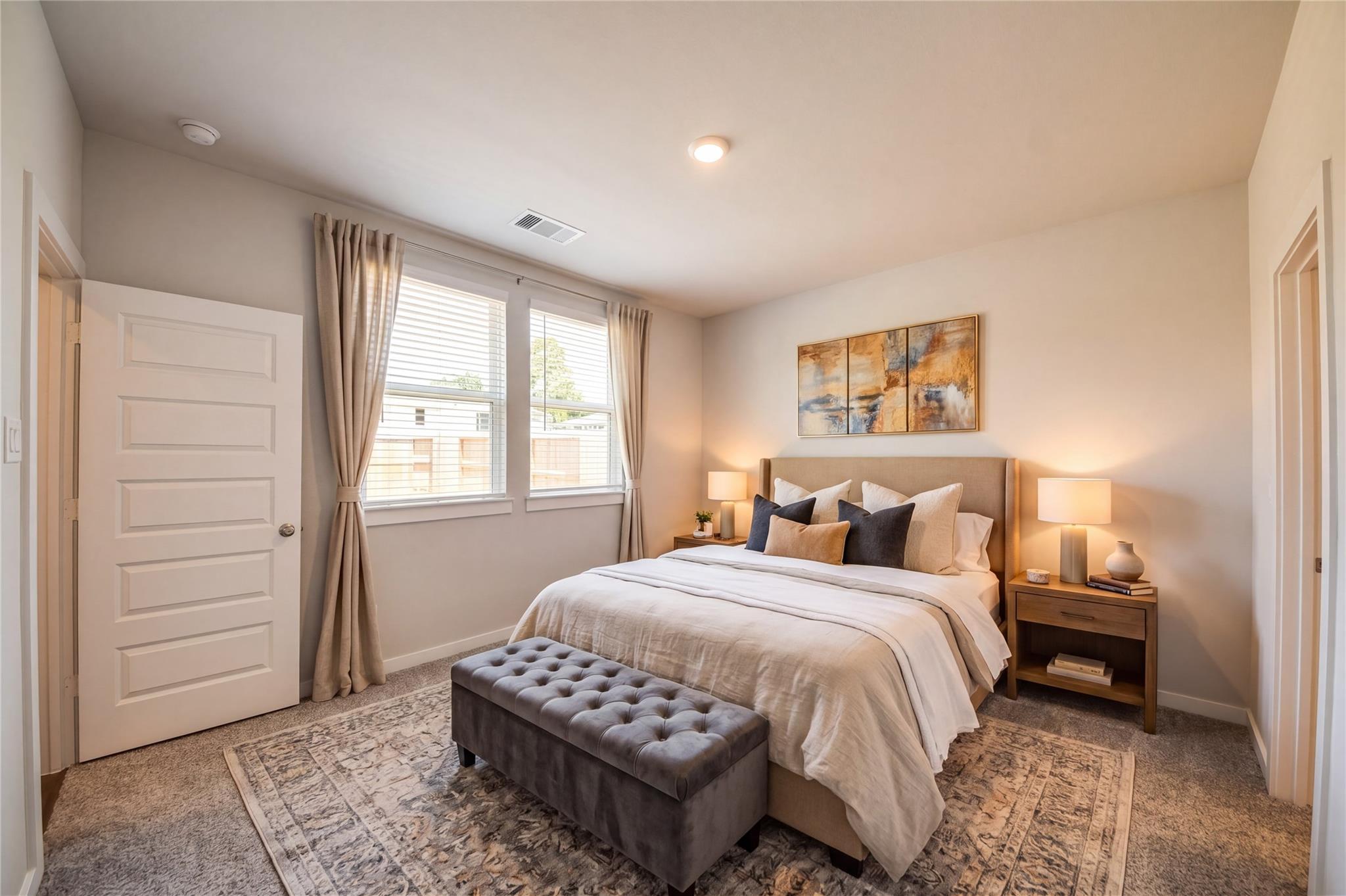 Bright primary bedroom with upholstered bed, tufted bench, and natural light in Davidson Homes The Frio F, Robins Landing Houston