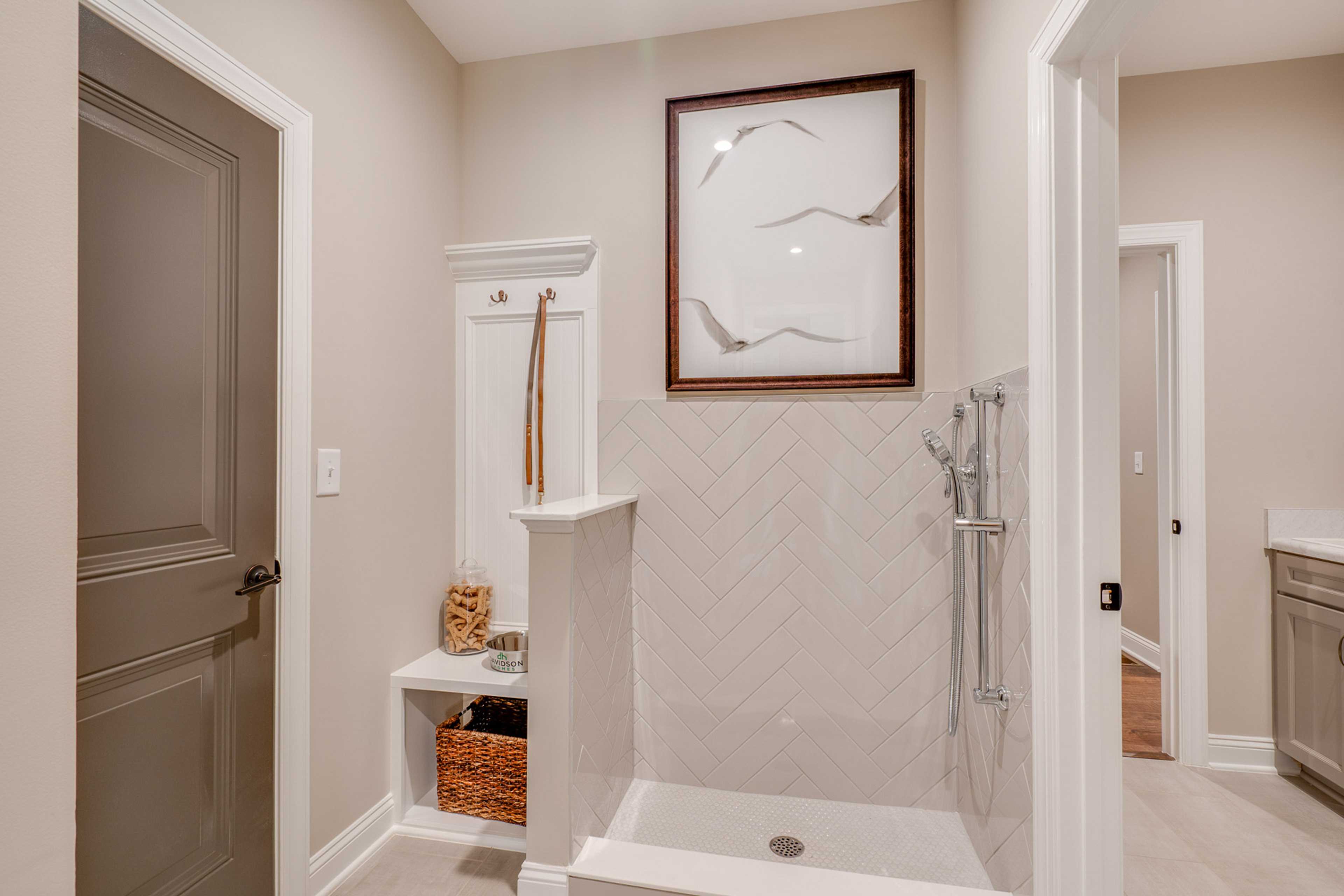 Pet shower station with herringbone subway tile, built-in bench, hooks and storage in Hasentree home, Wake Forest NC