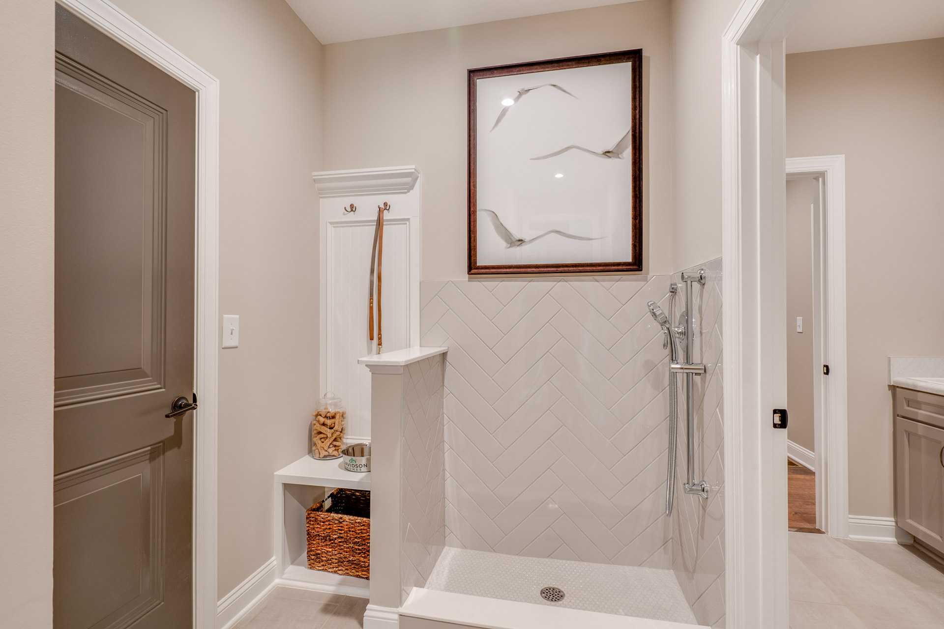Pet shower station with herringbone subway tile, built-in bench, hooks and storage in Hasentree home, Wake Forest NC