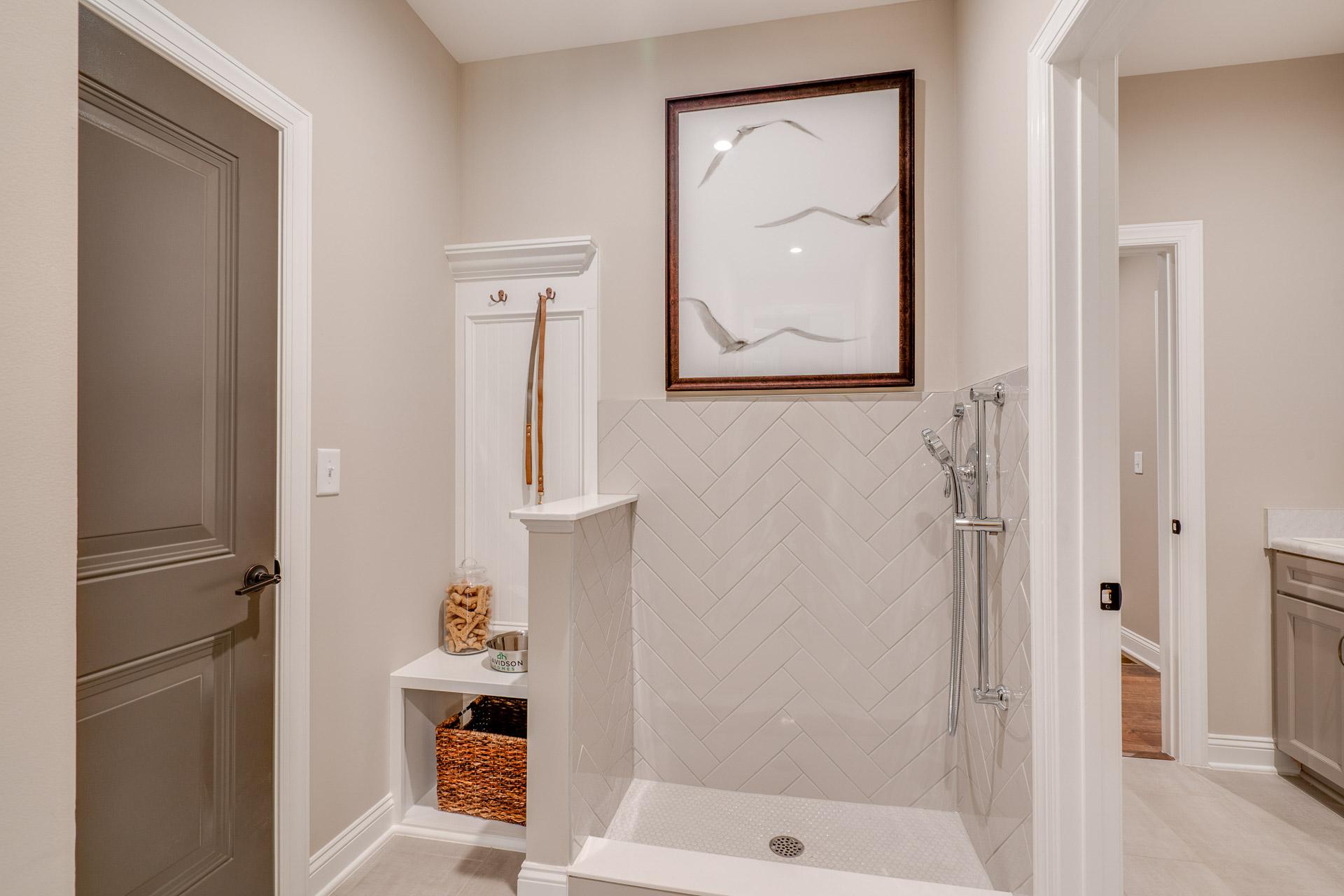 Pet shower station with herringbone subway tile, built-in bench, hooks and storage in Hasentree home, Wake Forest NC