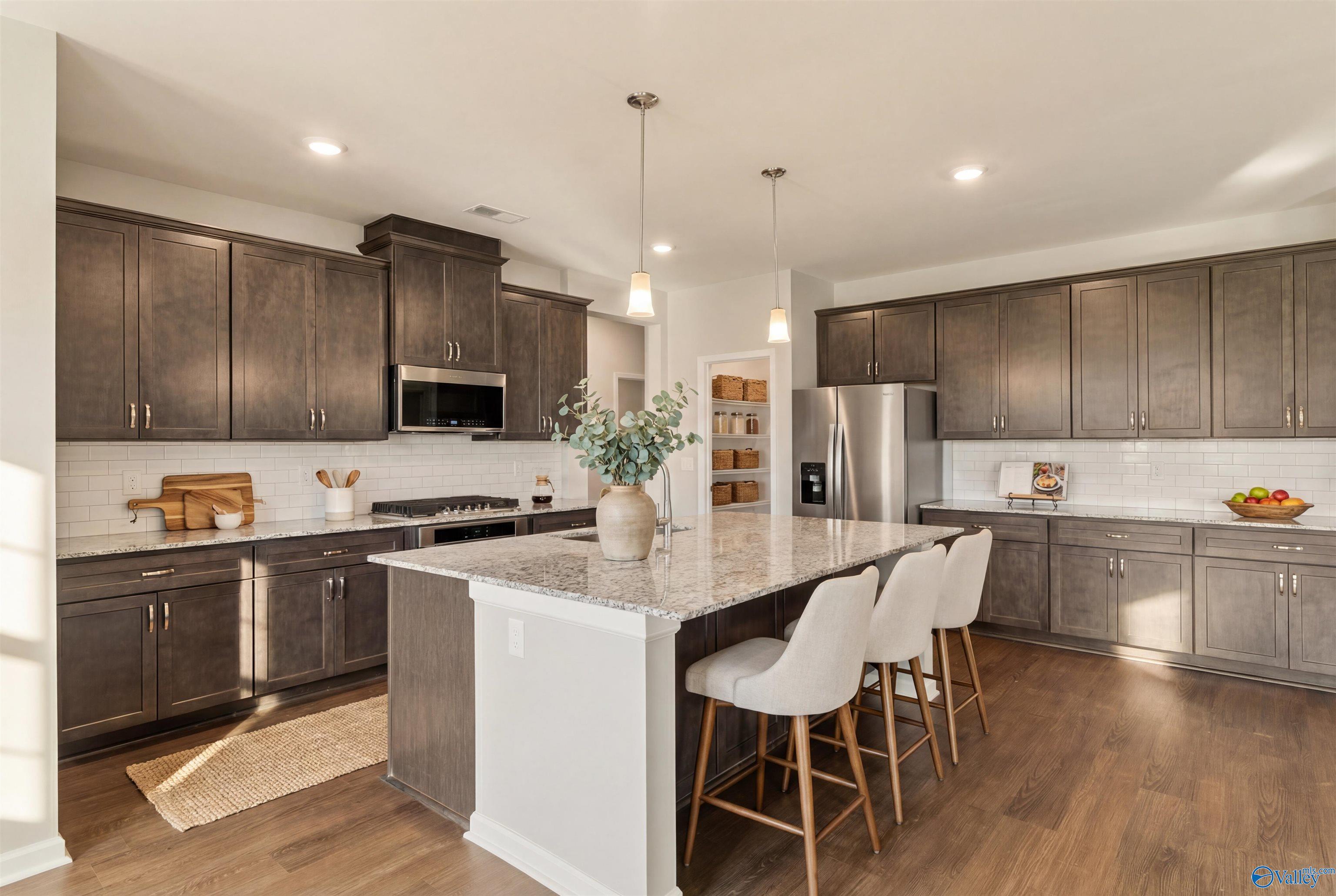 Modern kitchen with dark shaker cabinets, granite island, stainless appliances in Davidson Homes The Sanctuary, Huntsville AL