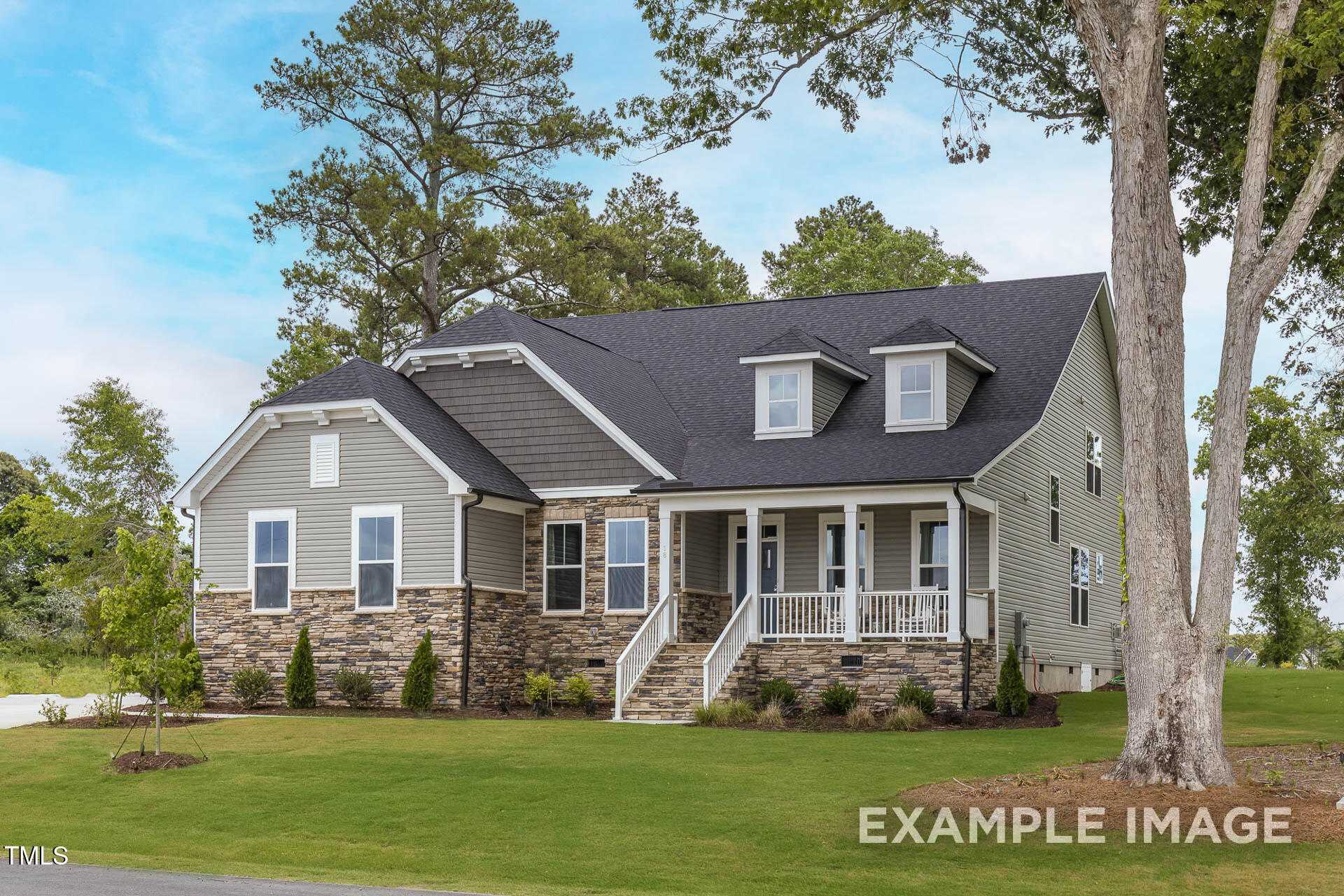 Two-story Magnolia B home by Davidson Homes with stone accents, columned porch, and 2-car garage amid lush pines in Lillington, NC