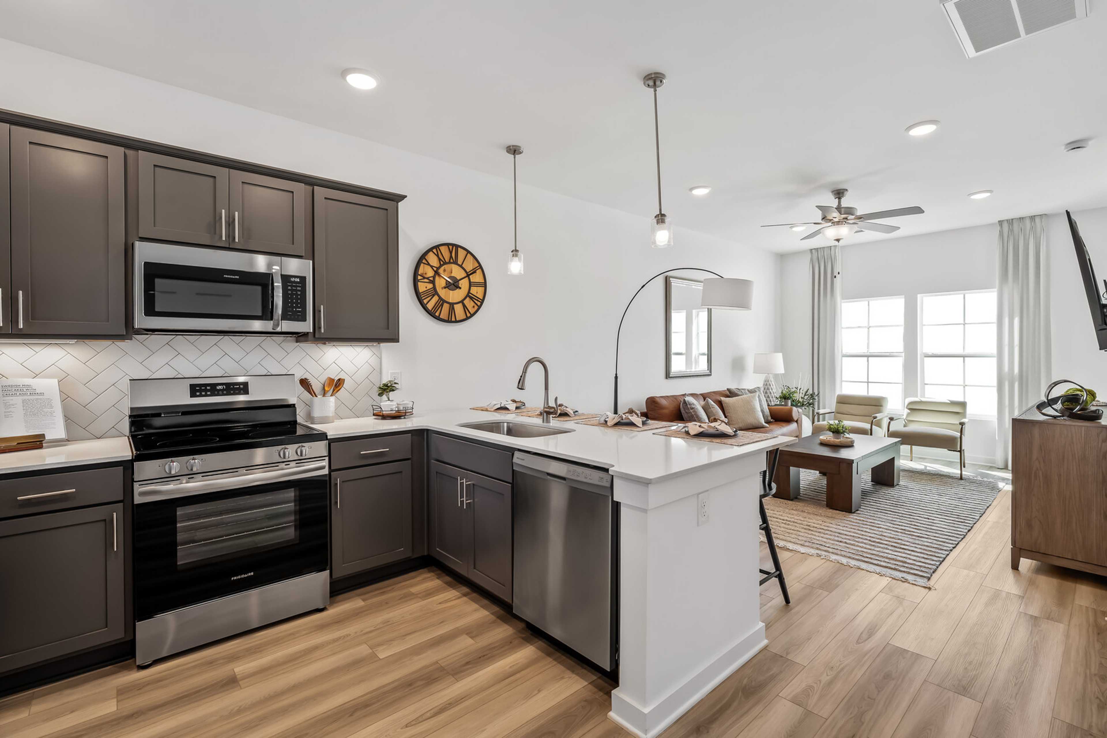 Open-concept kitchen and living room at The Towns at Red River in Gallatin, TN featuring gray cabinets, stainless steel appliances, and hardwood floors