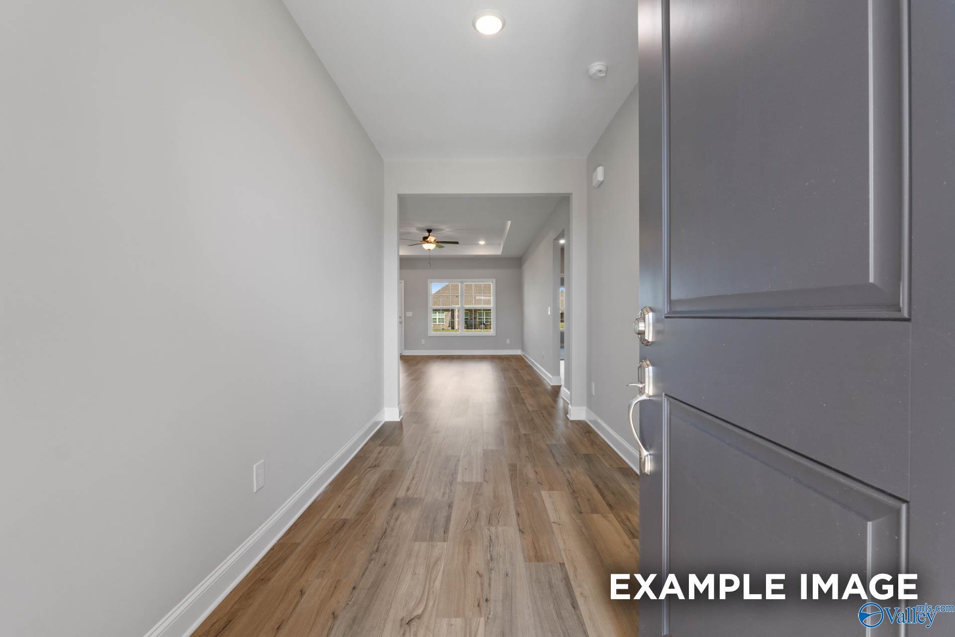 Bright hallway with gray walls, hardwood floors, and open doorways in Davidson Homes The Montgomery B, Hartselle, Alabama