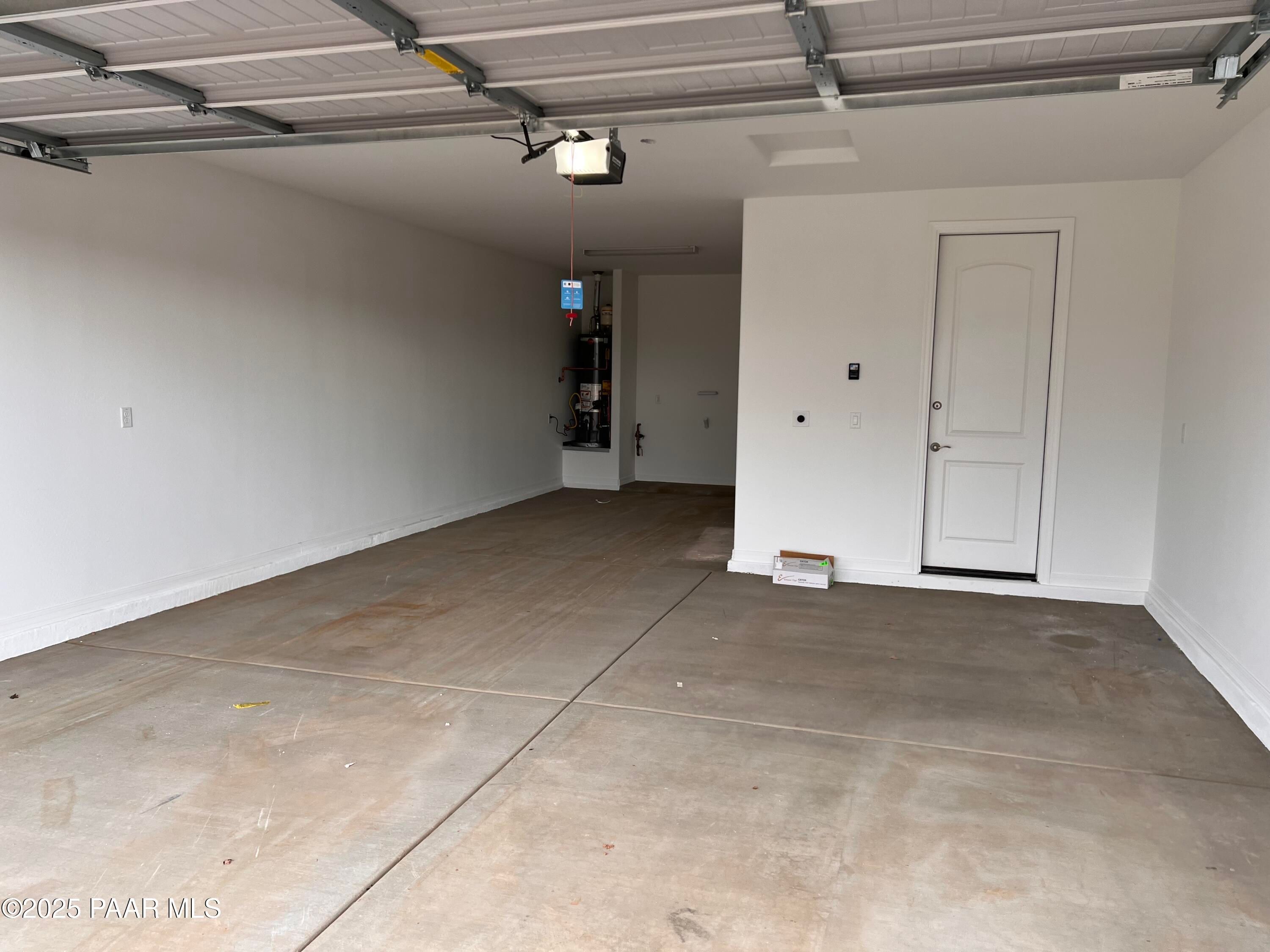 Spacious 3-car garage with concrete floor, built-in shelves, and interior door in Davidson Homes The Harmony A, Prescott Valley, Arizona