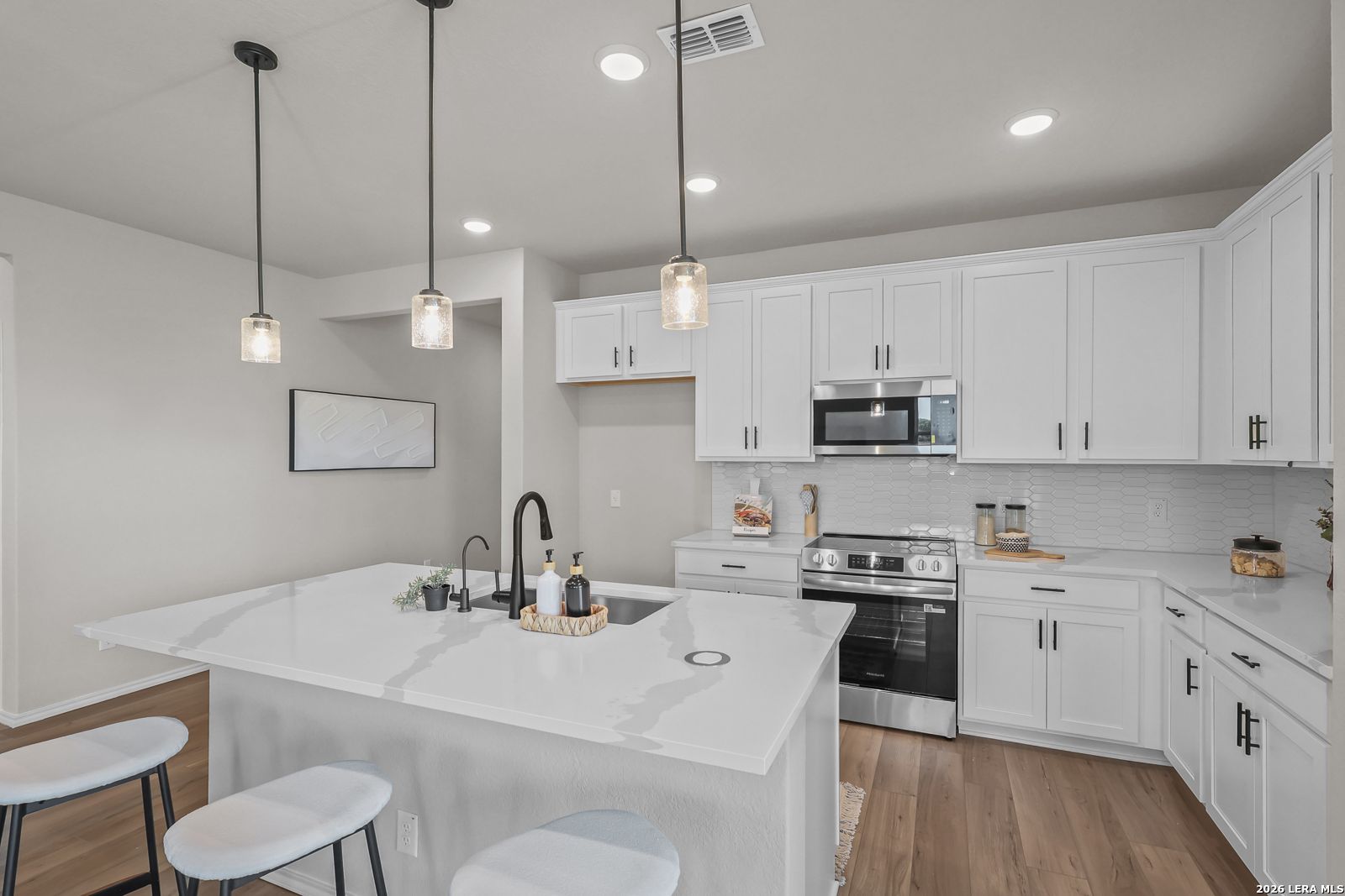 Modern kitchen with white cabinets, quartz island, and pendant lighting in The Daphne H home at Hannah Heights, Seguin, TX.
