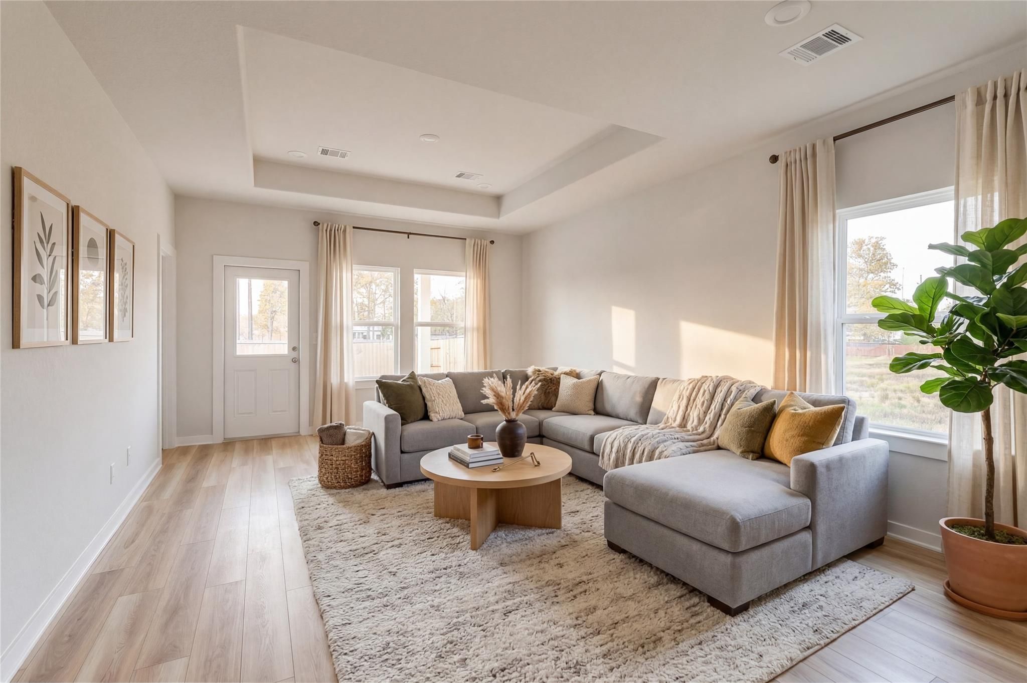Bright living room with tray ceiling in The Colorado G floor plan at Windmill Estates, Magnolia, Texas.