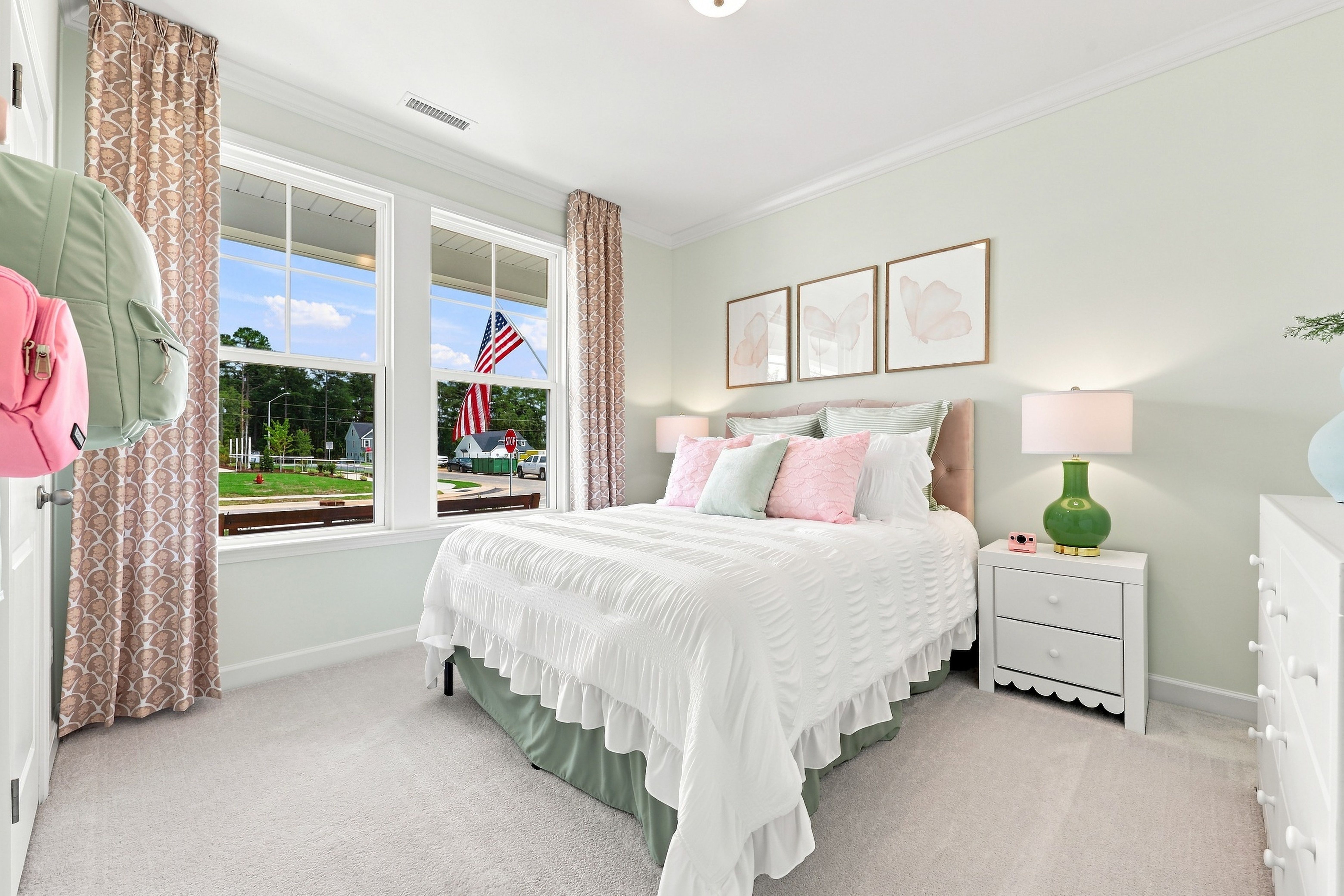 Bright and airy bedroom in The Daphne home design featuring soft pastel decor, white bedding, and large windows.