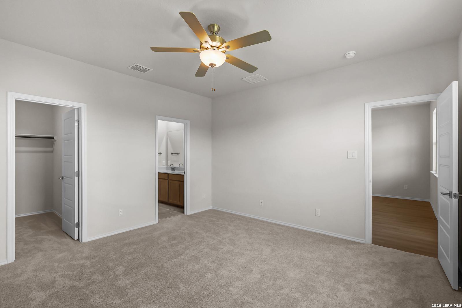 Spacious bedroom with ceiling fan, walk-in closet, and ensuite bath in The San Marcos F, Davidson Homes, San Antonio, TX.