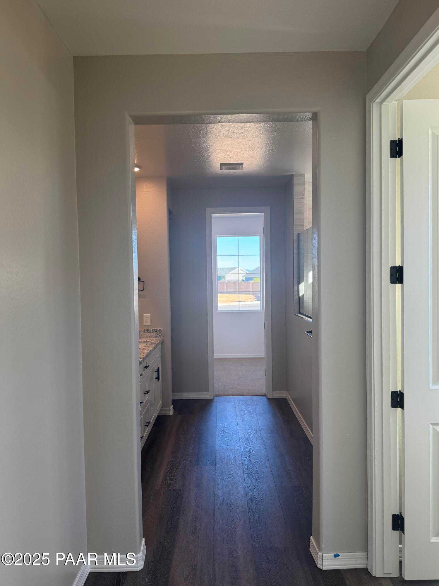 Bright hallway leading to modern bathroom with double vanity and backyard hot tub view in Davidson Homes The Monarch E, Prescott, Arizona