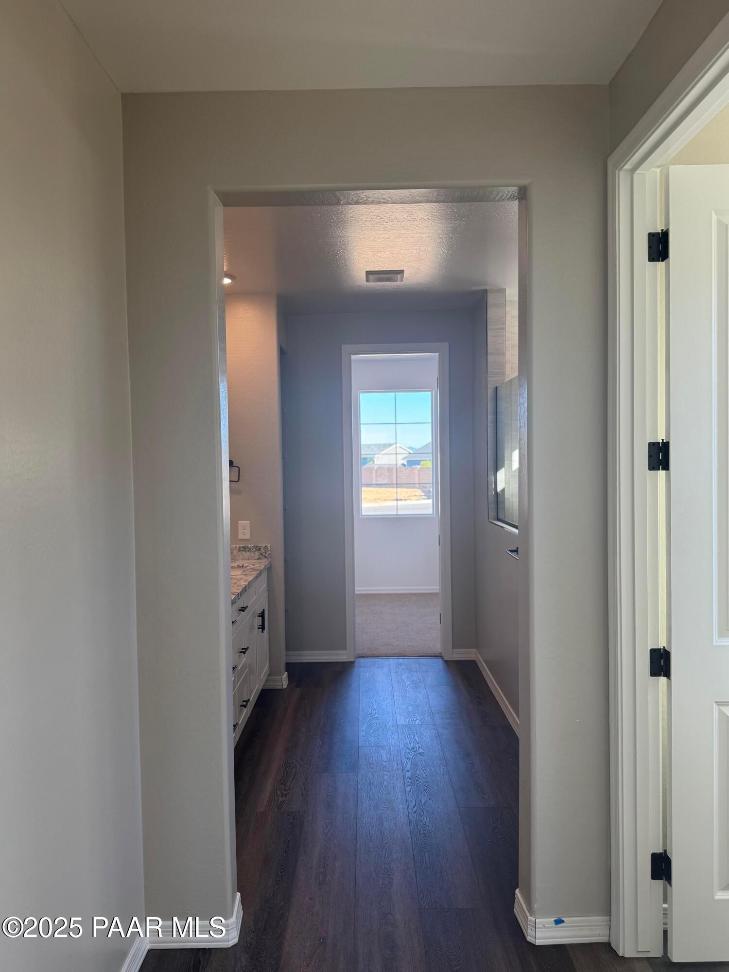 Bright hallway leading to modern bathroom with double vanity and backyard hot tub view in Davidson Homes The Monarch E, Prescott, Arizona