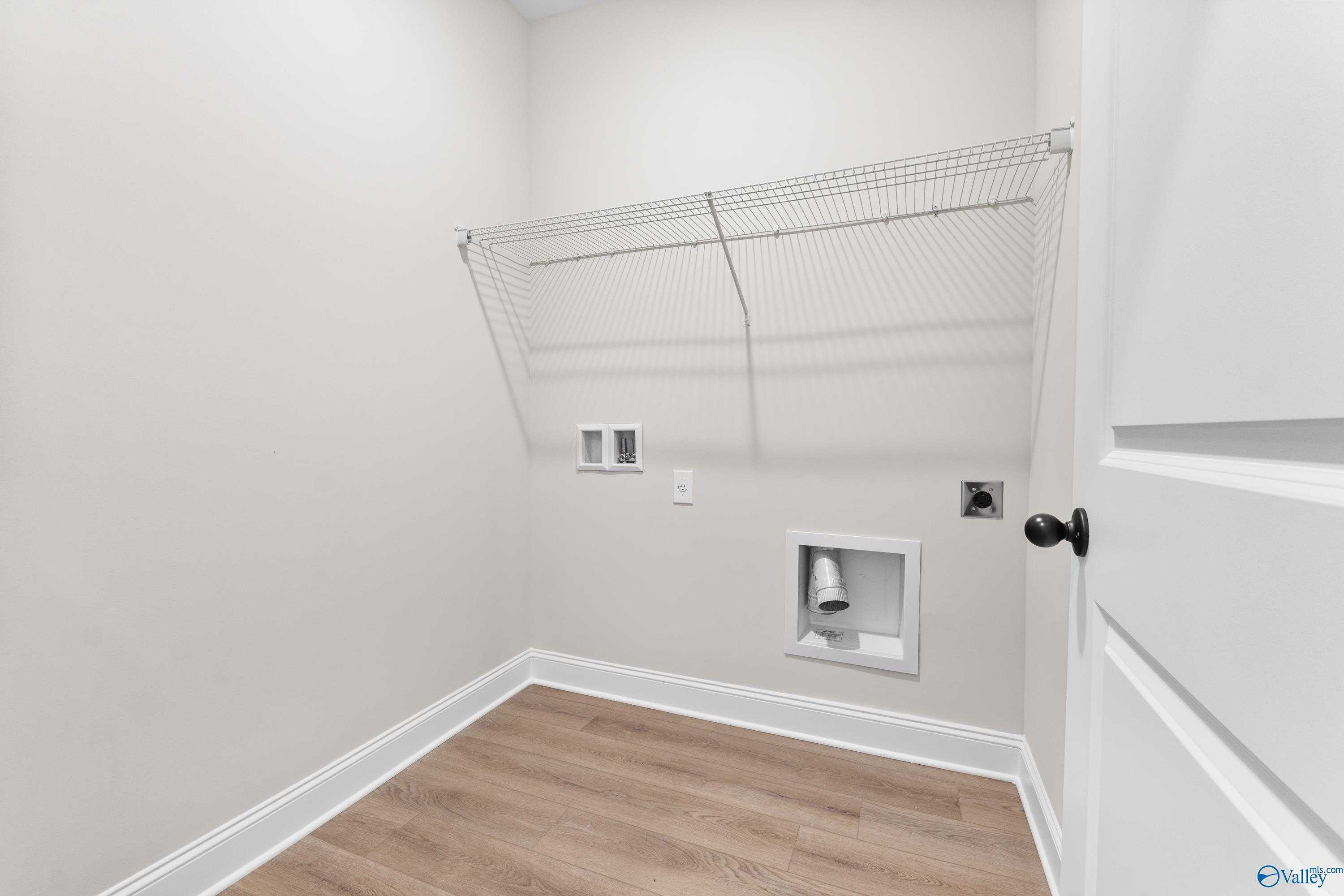 Functional laundry room with wire shelving, washer-dryer hookups and wood flooring in Davidson Homes The Franklin B, Hazel Green, Alabama