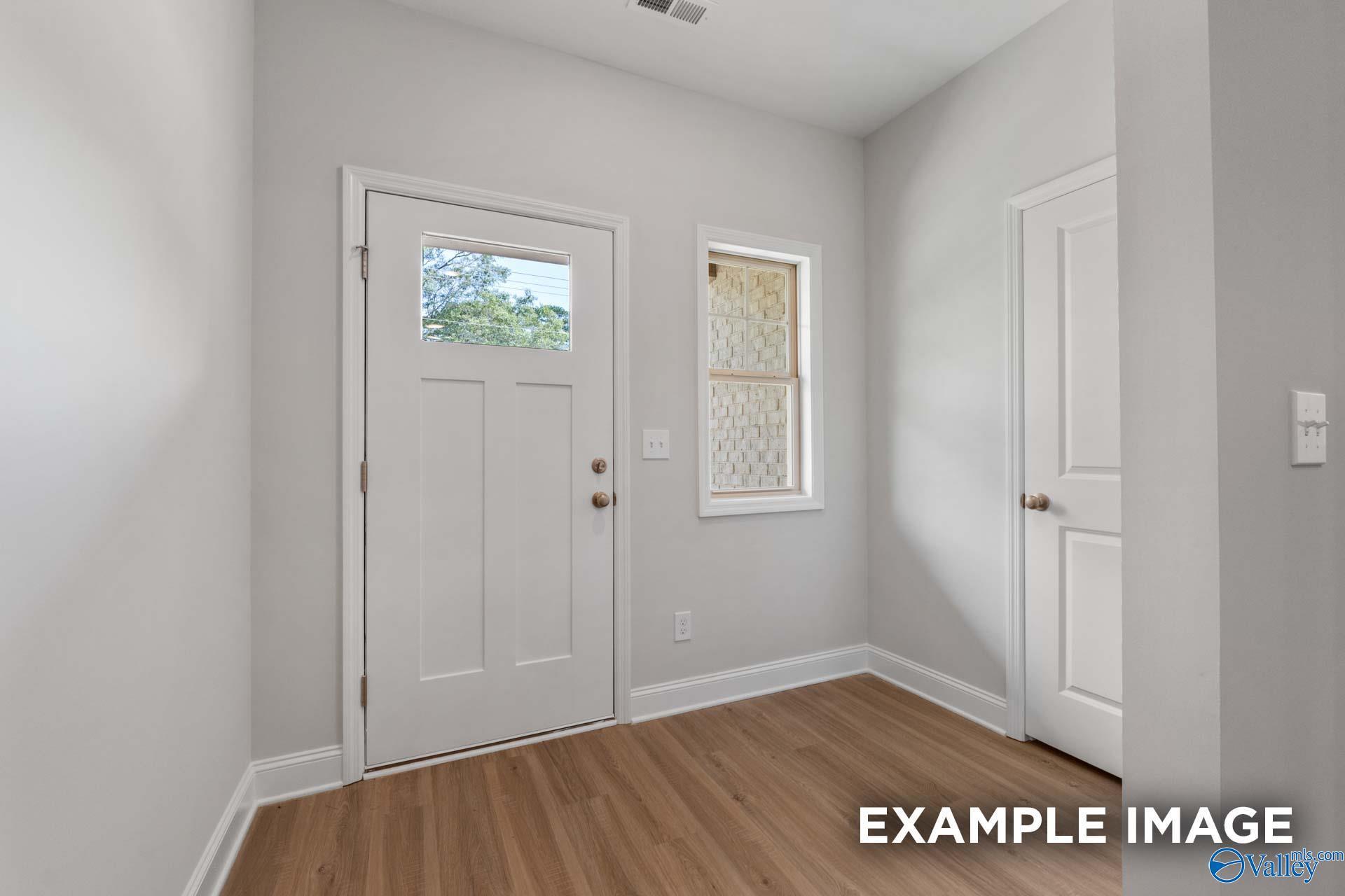 Bright entryway featuring light gray walls, hardwood floors, and windowed front door in Davidson Homes The Camilla C, Hartselle, Alabama