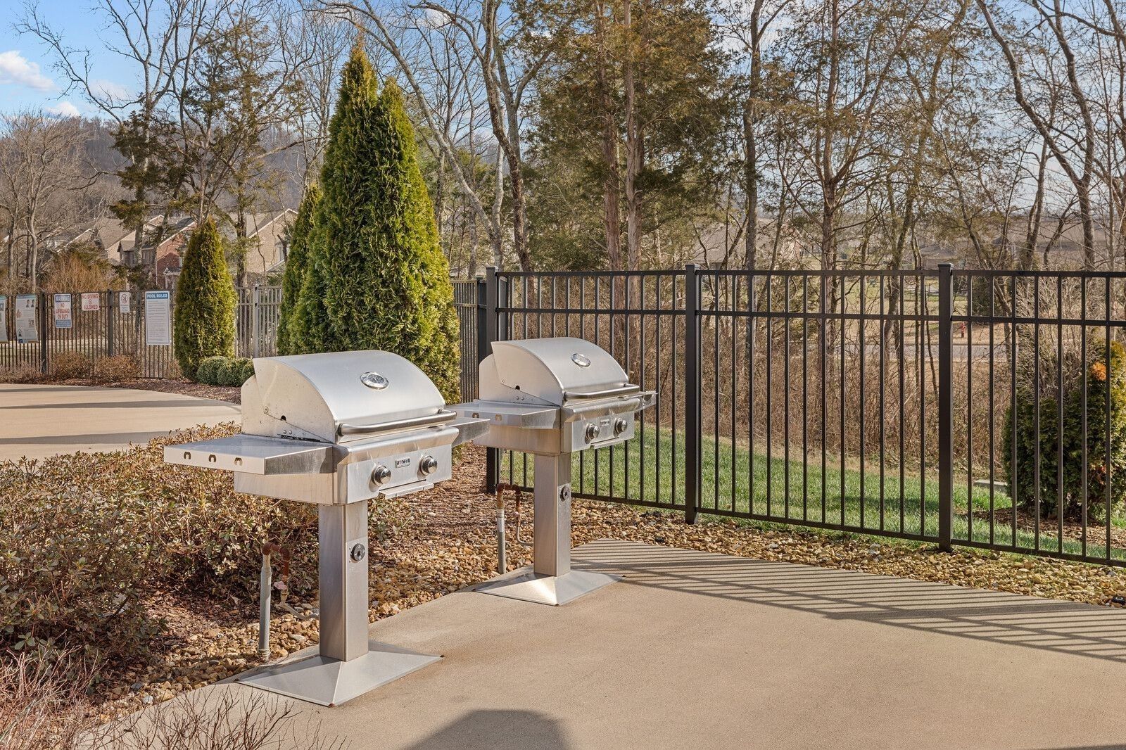Stainless steel double grills on concrete patio with black fence, lush trees, and green yard in Carellton, Gallatin, Tennessee