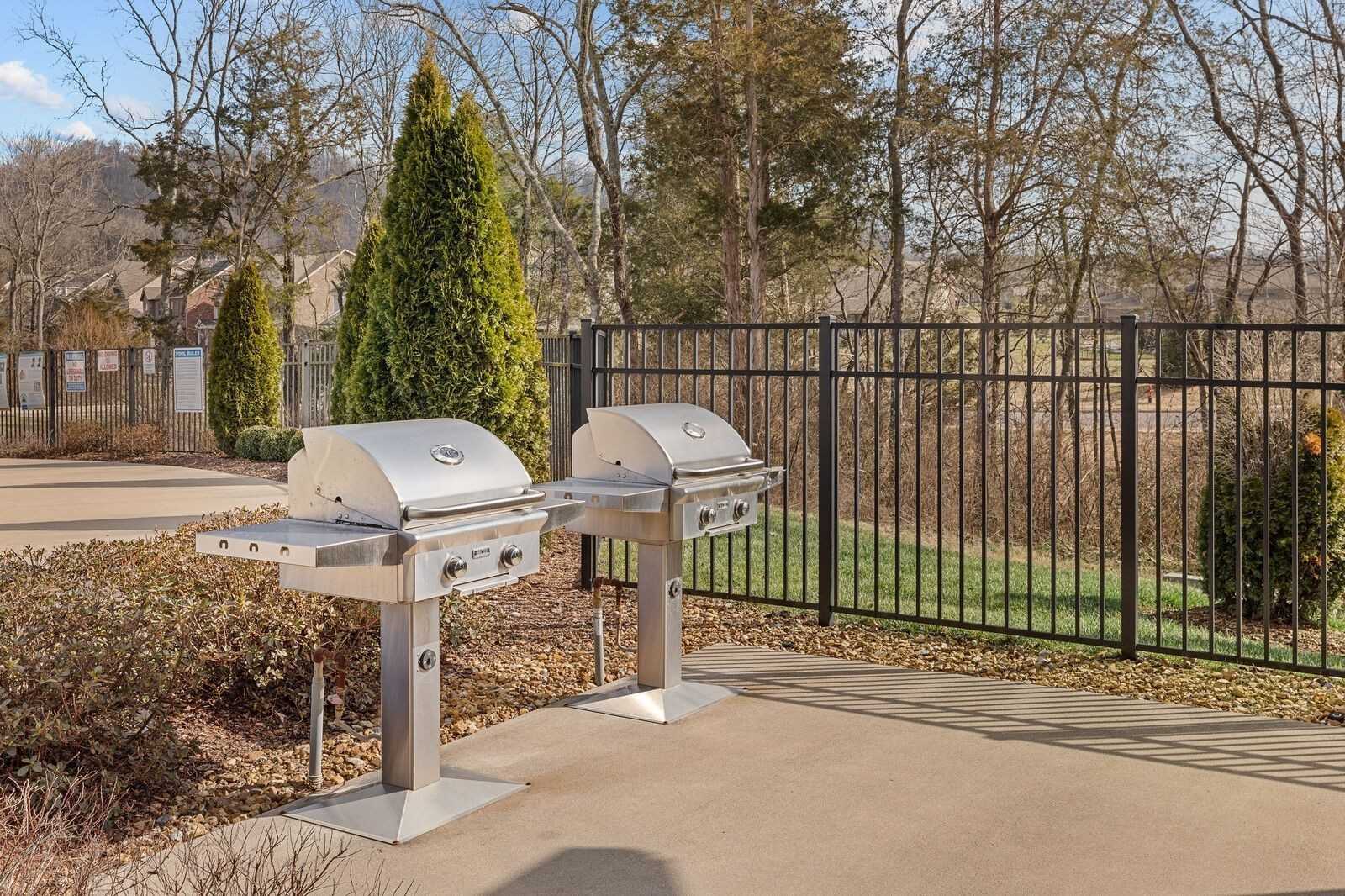 Stainless steel double grills on concrete patio with black fence, lush trees, and green yard in Carellton, Gallatin, Tennessee