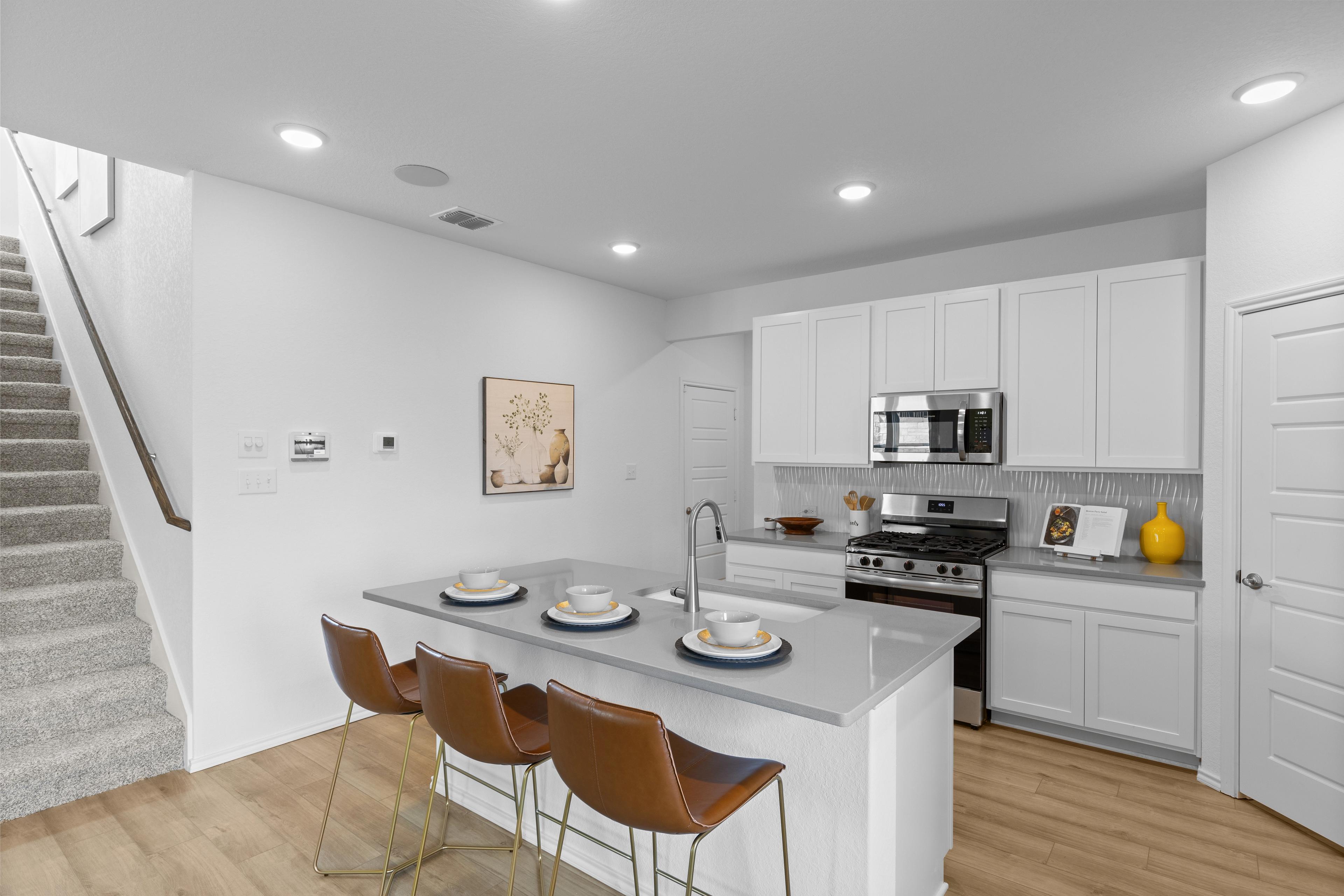 Modern open-concept kitchen at Horizon Pointe in Converse Texas with white cabinets quartz island and leather bar stools