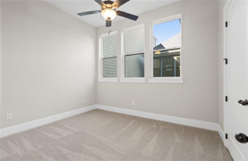 Bright bedroom with light gray walls, triple windows, beige carpet, and ceiling fan in Davidson Homes The Seaside A, Woodstock, GA