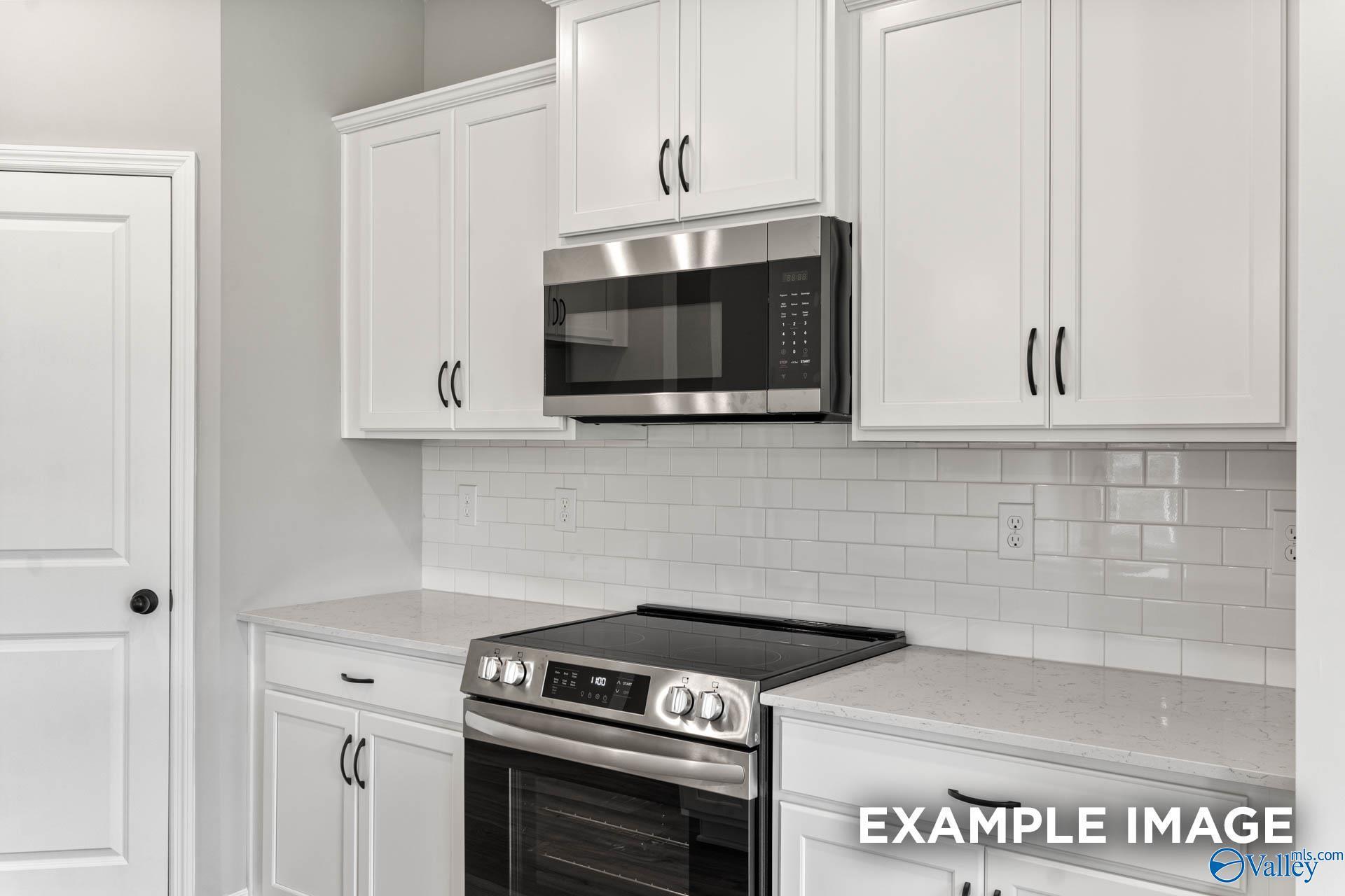 Contemporary kitchen with white shaker cabinets, quartz countertops, stainless oven and microwave in Davidson Homes The Franklin C, Athens AL