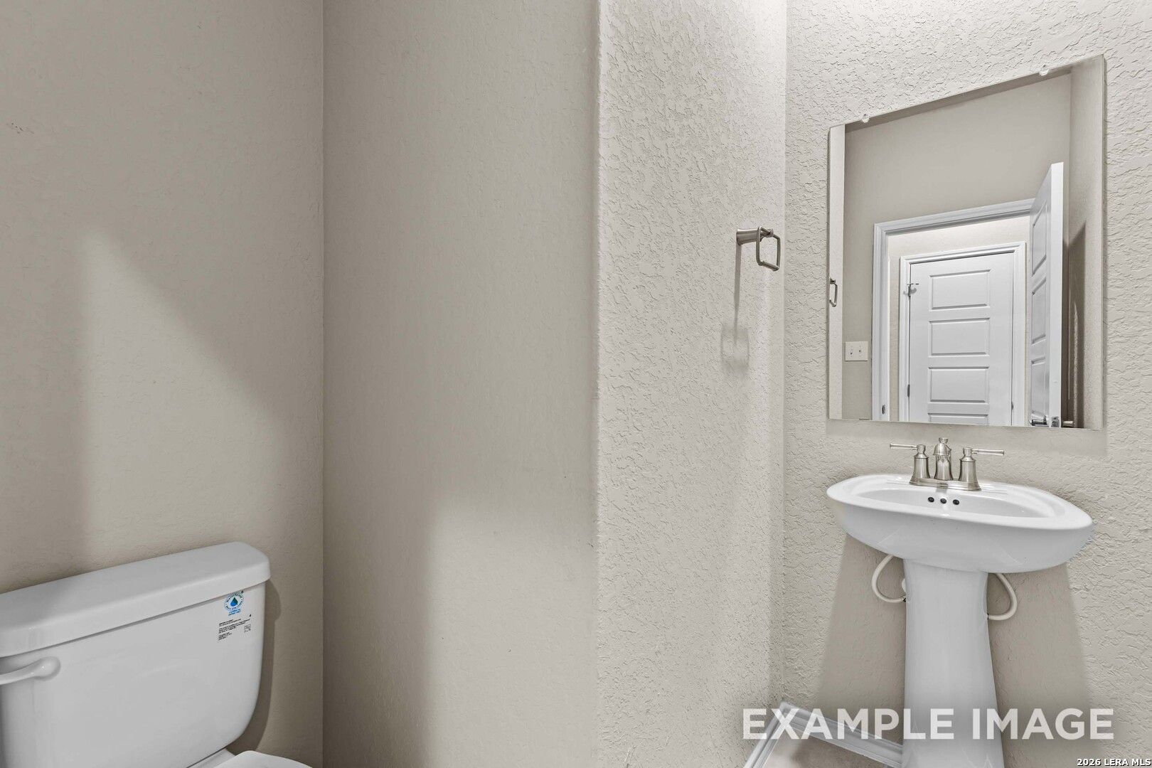 Half-bath with pedestal sink and mirror in The Douglas F floor plan by Davidson Homes in Bricewood, San Antonio, Texas.