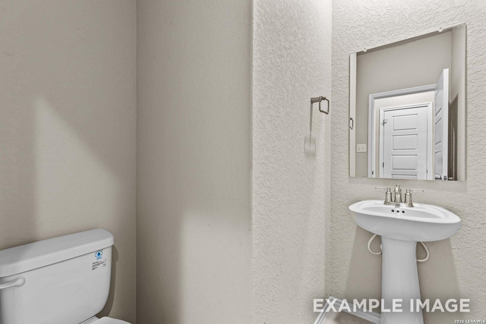 Half-bath with pedestal sink and mirror in The Douglas F floor plan by Davidson Homes in Bricewood, San Antonio, Texas.