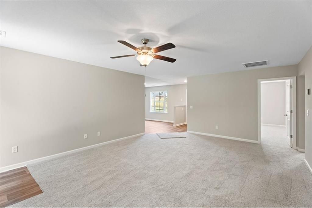 Spacious empty living room with ceiling fan, neutral walls, and open layout in The Washington 3-bedroom home, Phenix City, Alabama