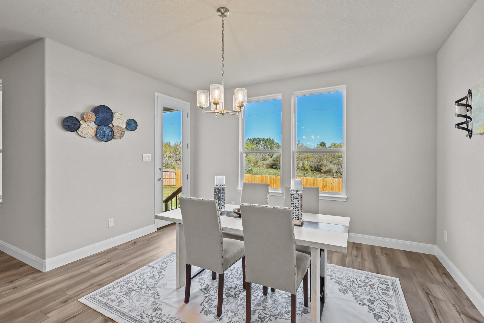 Bright dining area in The Jennings G featuring modern chandelier, wood-style flooring, and backyard access.