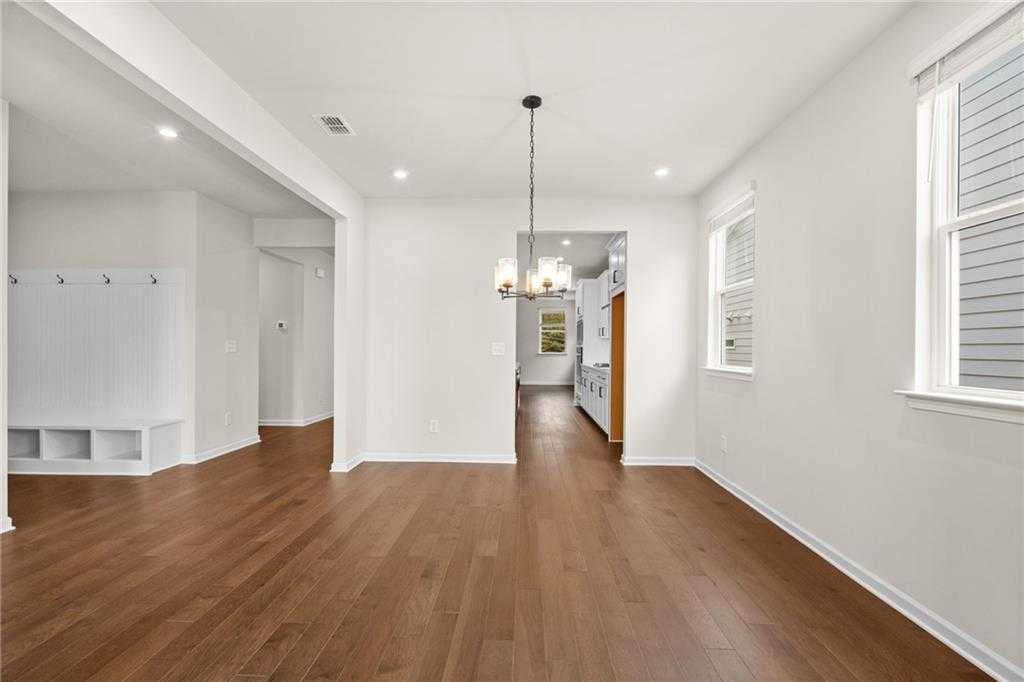 Bright open entryway with hardwood floors, white built-in bench, and chandelier leading to kitchen in Davidson Homes The Glenwood C, Loganville, GA