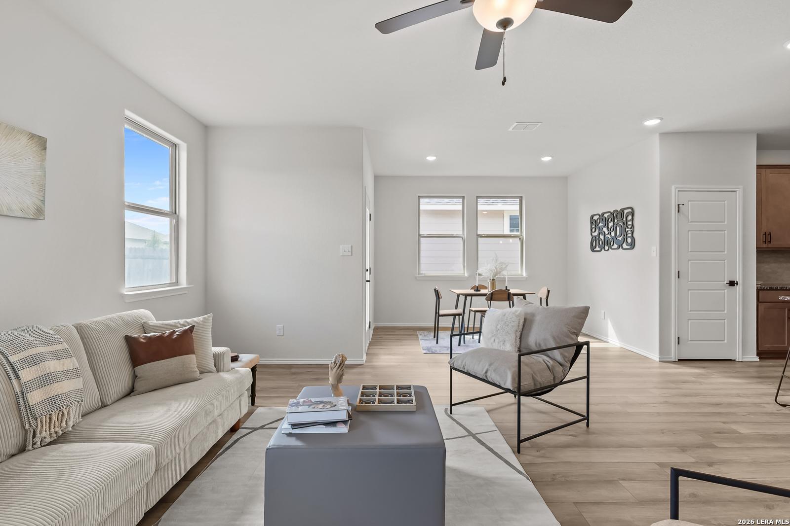 Bright open living room with beige sofa, coffee table, and dining area in Davidson Homes The Daphne H, Seguin, Texas